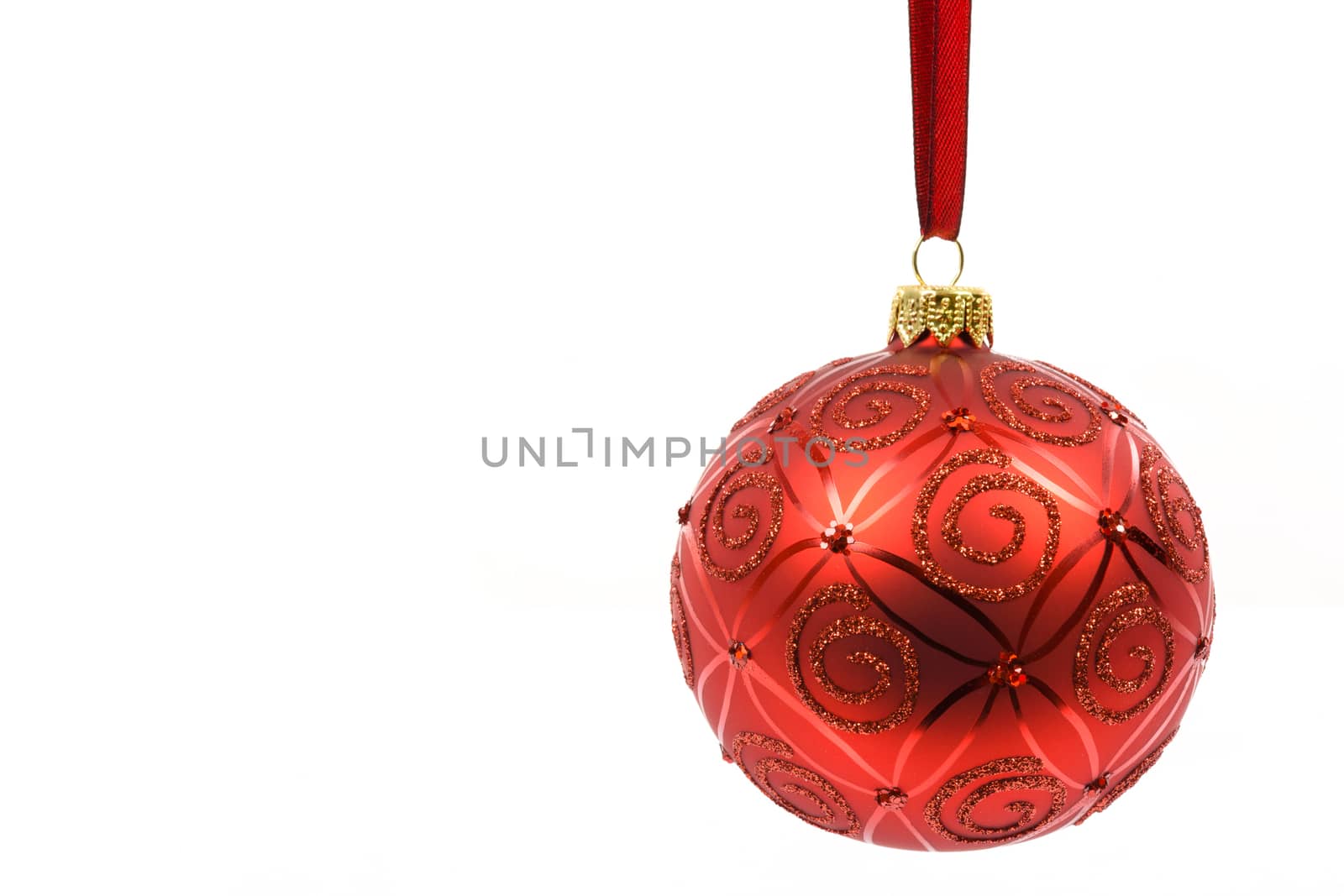 Perfect and ideal red glass Christmas ball hanging on a red ribbon on a white background in close-up