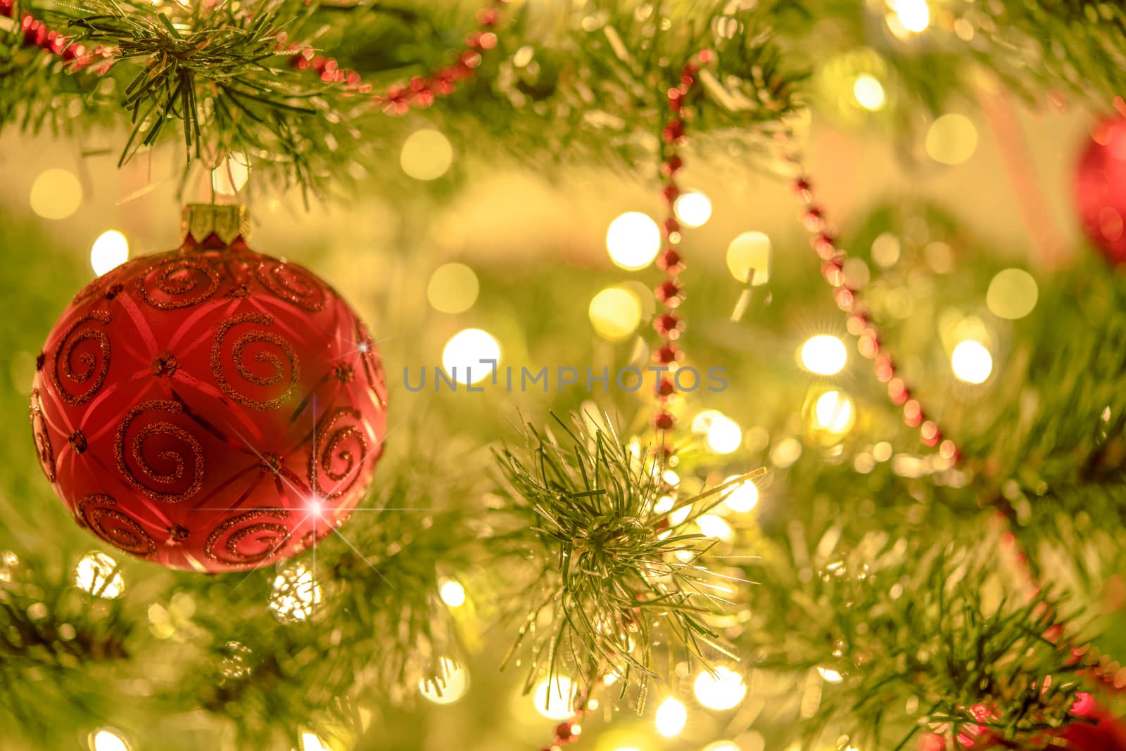 Beautiful Christmas background - red bauble on a background of blurred lights on a Christmas tree with bokeh effect.