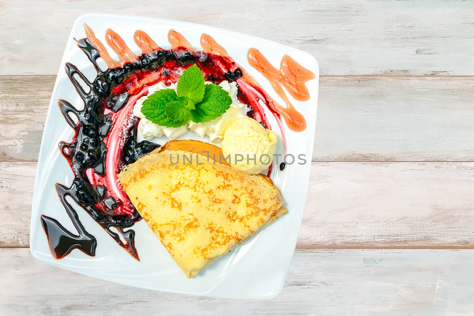 Composite image of a sweet dessert - pancakes with ice cream, whipped cream and mint on a bright wooden table ( top view).