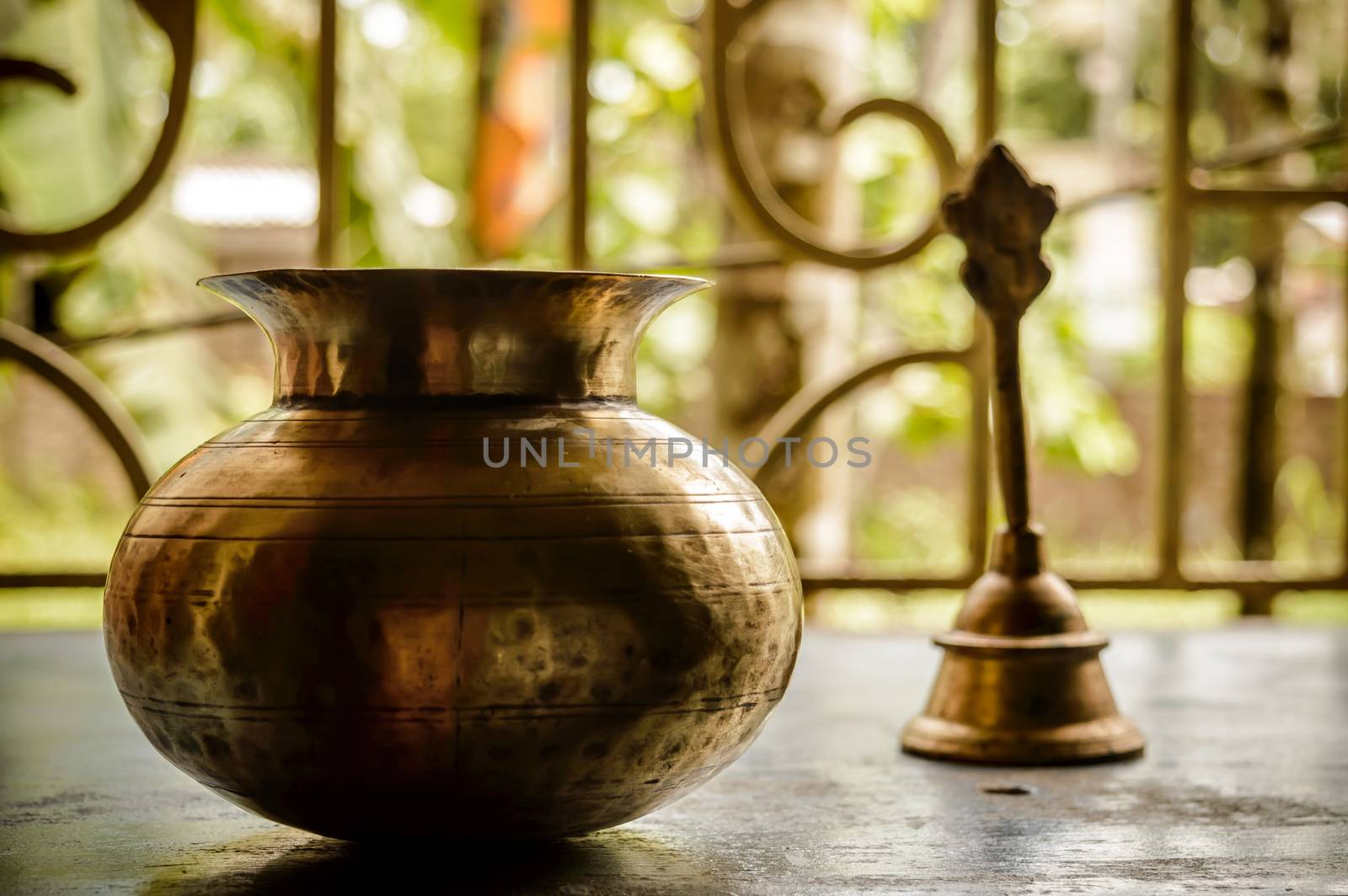 Close up Still Life of antique Holi water pot and bell on rustic floor. Faith, Tradition, Spirituality, Prayer, symbols of peace and Religious Themes. Arts and culture background concept. Copy space room for text for massage.