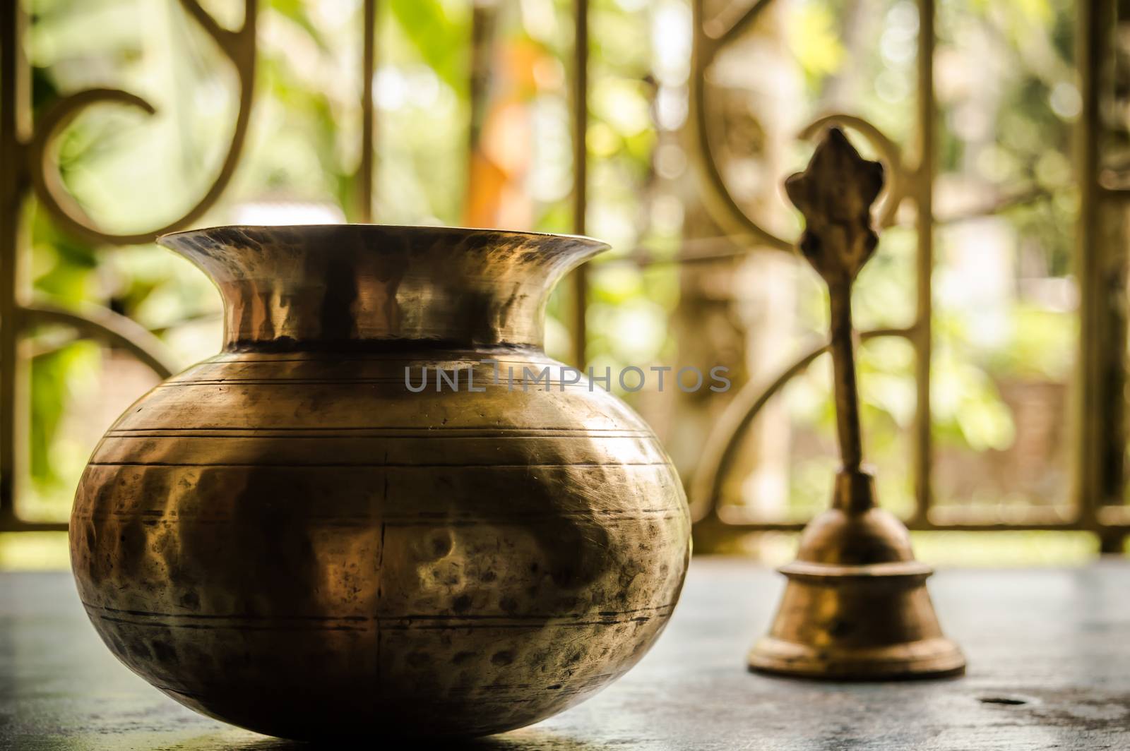 Close up Still Life of antique Holi water pot and bell on rustic floor. Faith, Tradition, Spirituality, Prayer, symbols of peace and Religious Themes. Arts and culture background concept. Copy space room for text for massage.