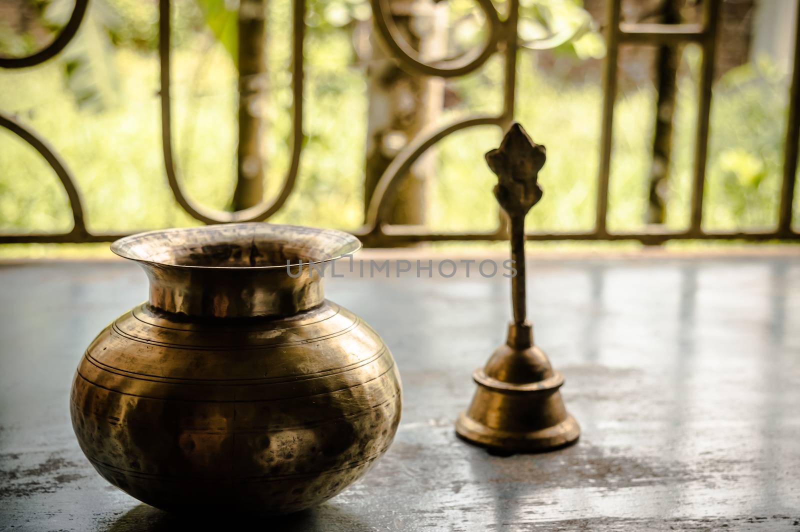 Close up Still Life of antique Holi water pot and bell on rustic floor. Faith, Tradition, Spirituality, Prayer, symbols of peace and Religious Themes. Arts and culture background concept. Copy space room for text for massage.