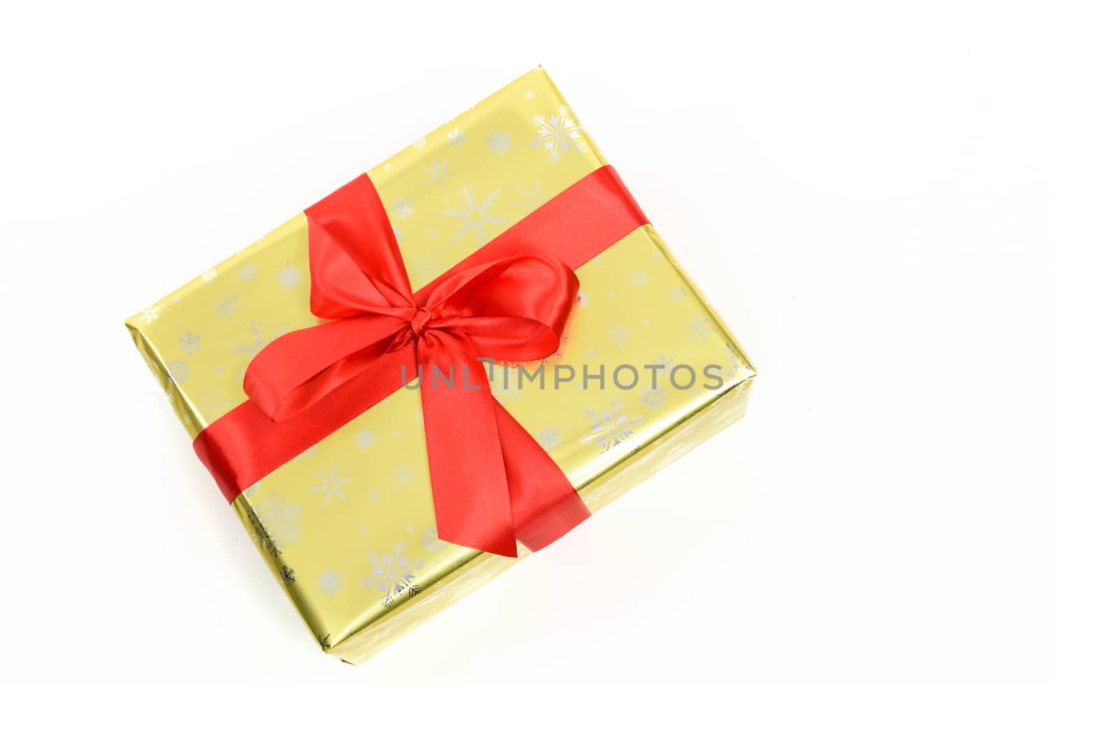 Concept of luxury Christmas gift - a box packed in a golden paper and tied with a red satin ribbon on a white background