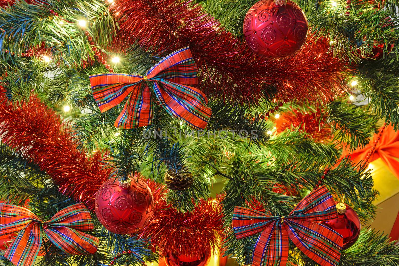 Beautiful Christmas decoration as a background - illumination of lights and red bows and baubles on a Christmas tree in close-up