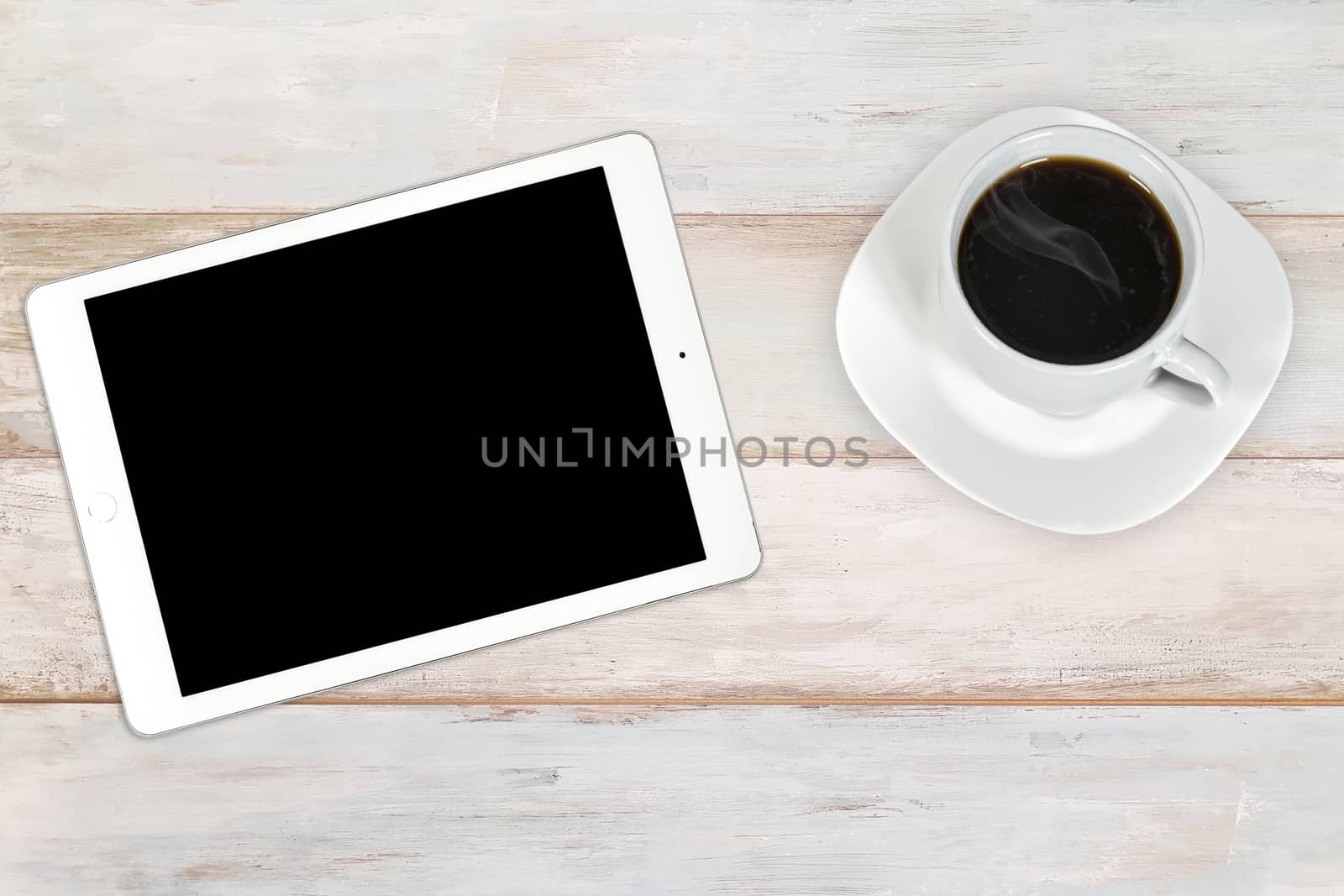Concept of creative workplace -  modern white and silver digital tablet with cup of coffee on a wooden bright background (high angel view)