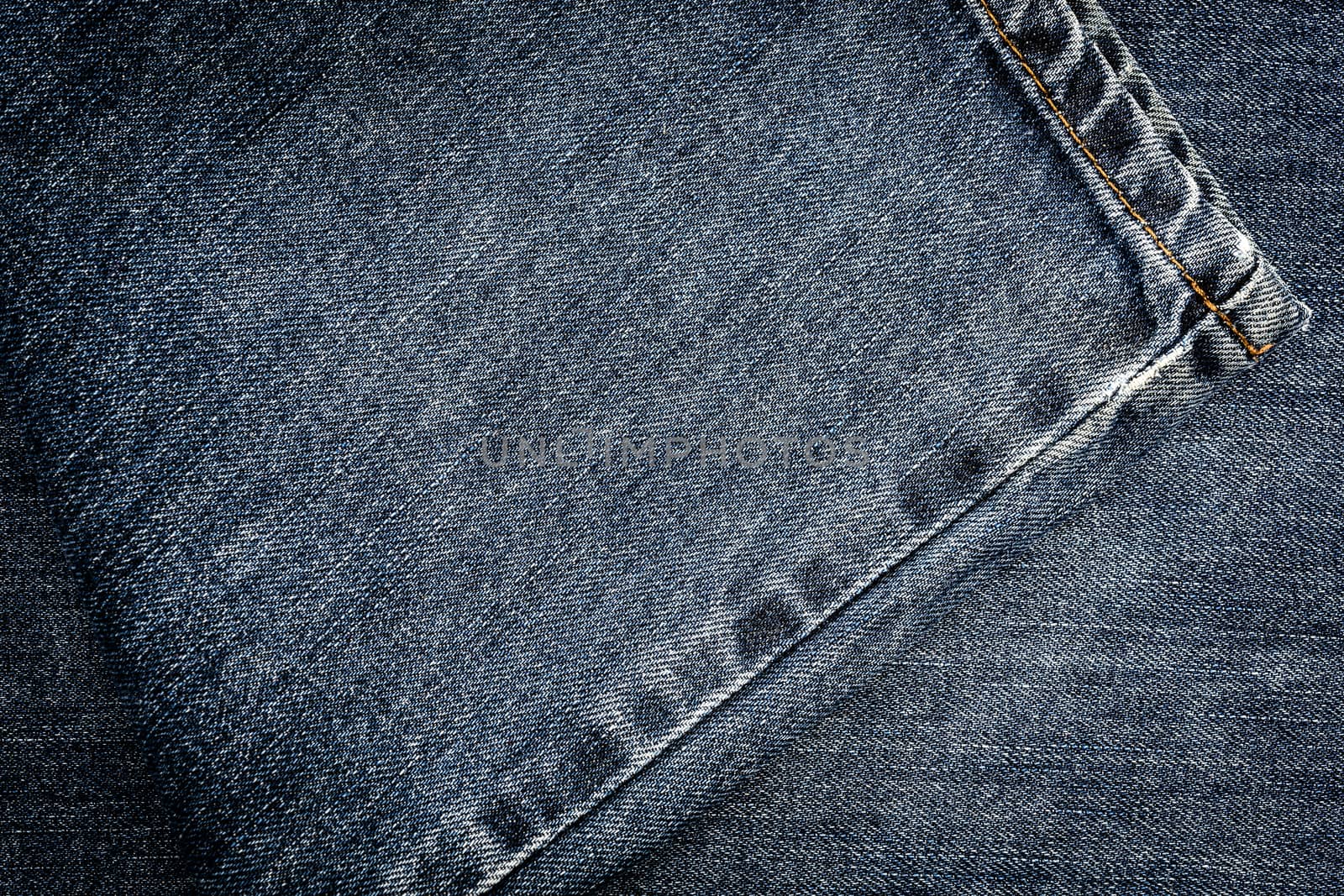 Textured vintage background - dirty blue jeans textile denim with seam of fashion design in close-up (high details).