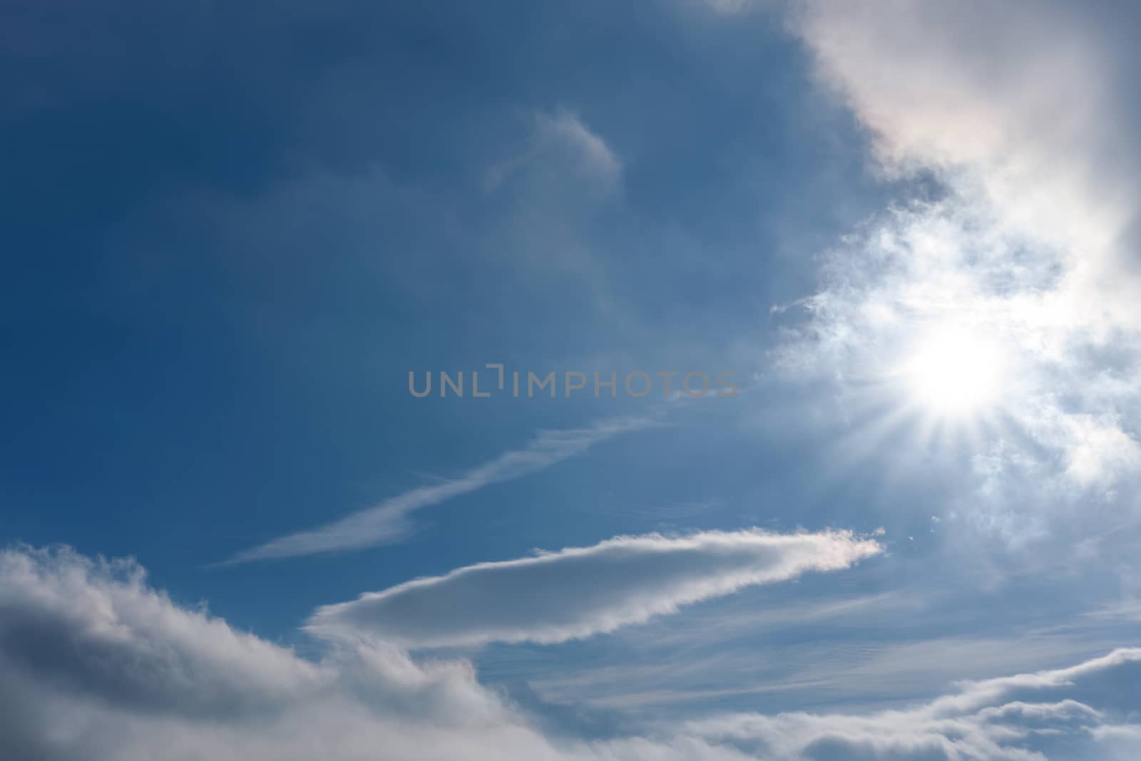 Beautiful and magical landscape flying above the clouds against a blue sky and sunshine