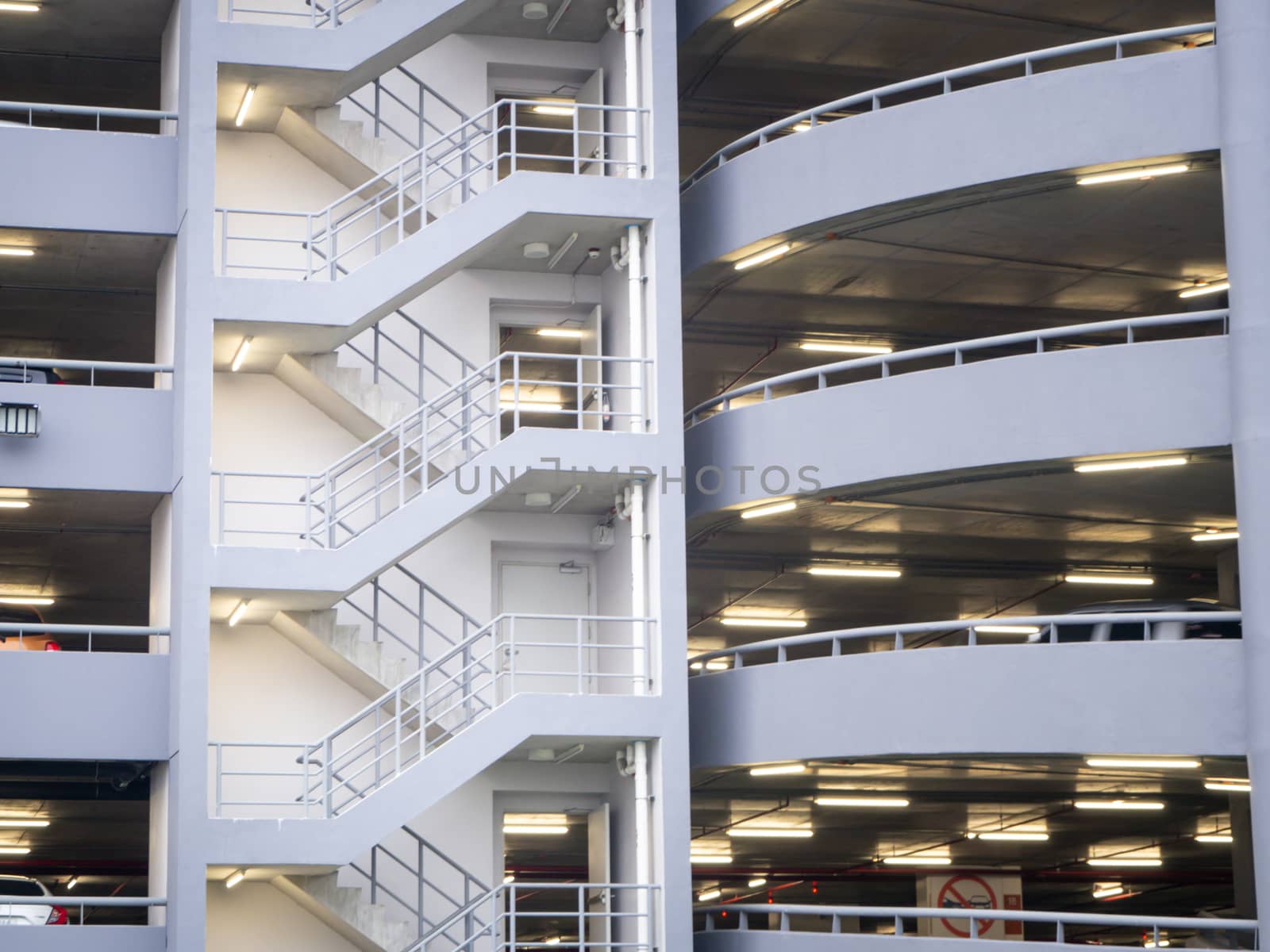 walking on the stair on the side of a white multi storey parking lots building