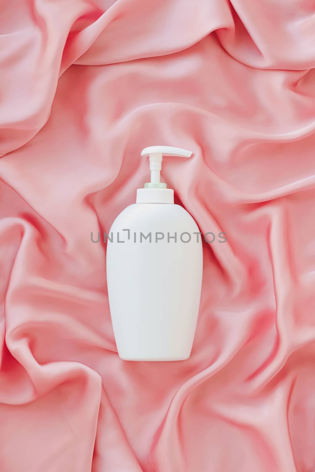 Blank label cosmetic container bottle as product mockup on pink silk background by Anneleven