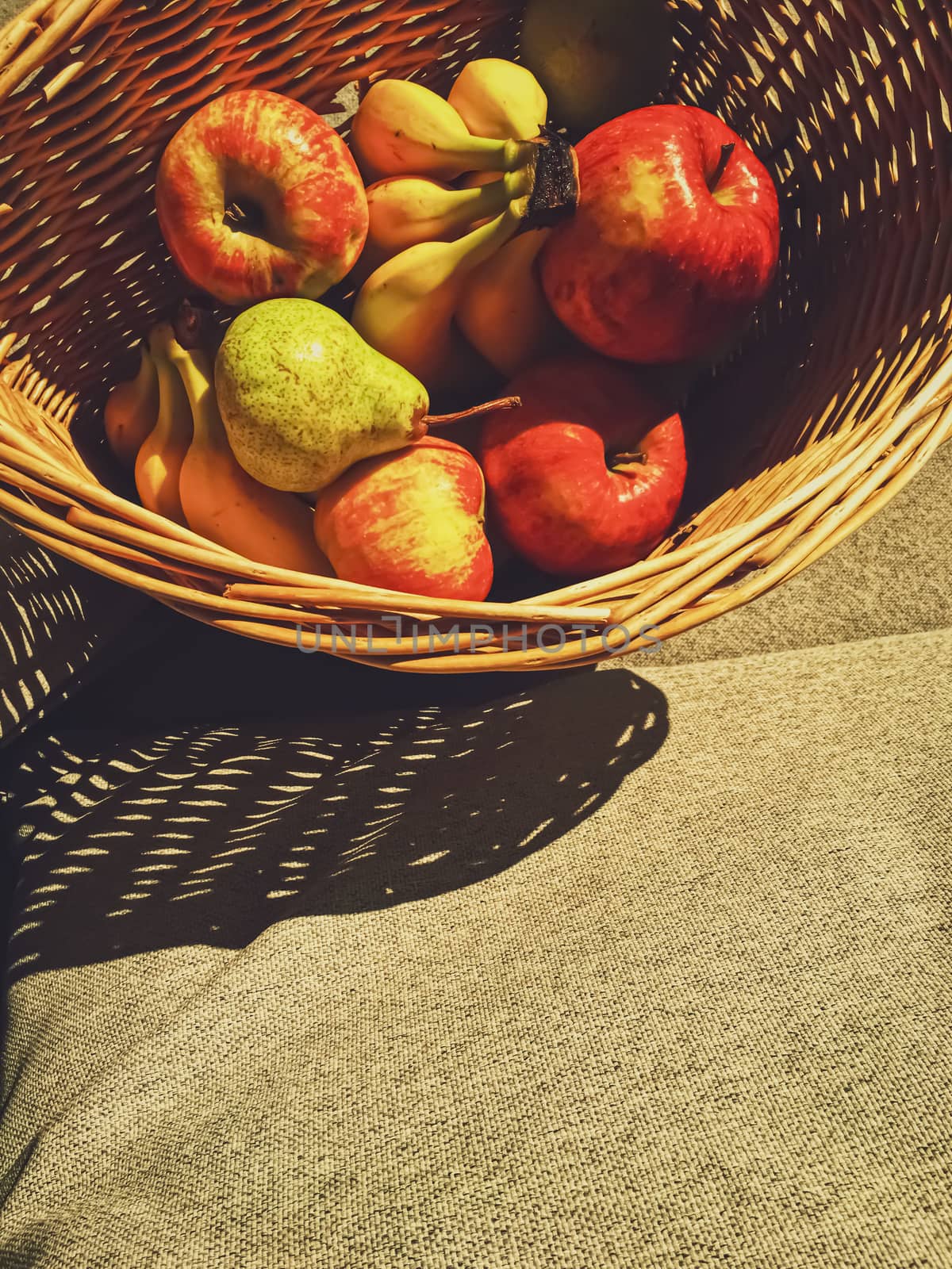 Organic apples, pears and bananas on rustic in a wicker basket by Anneleven