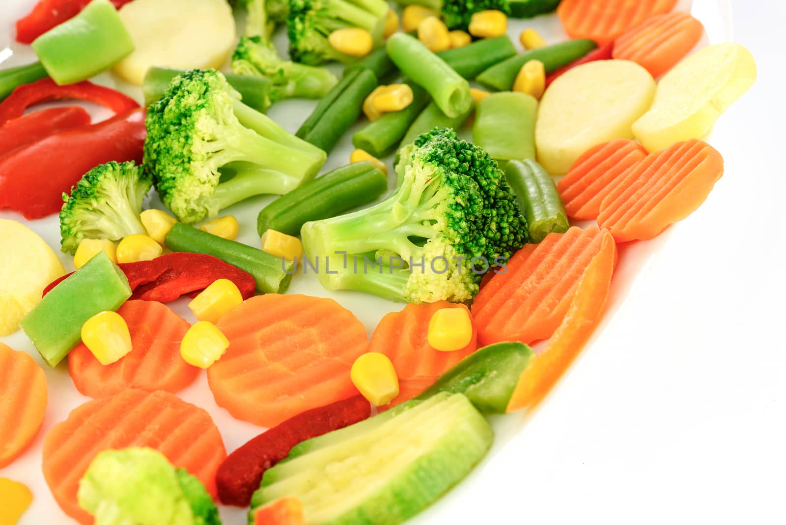 Mixed chopped fresh vegetables on the plate in close-up.