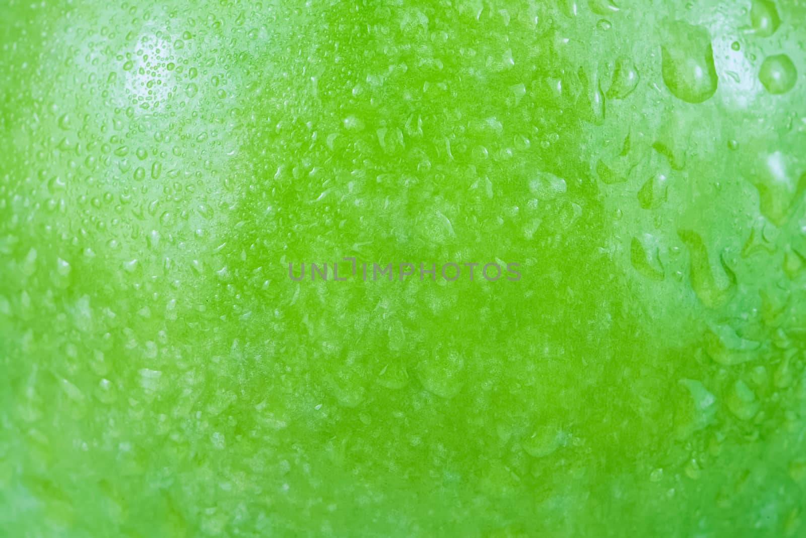 Water drops background on a green apple surface in close-up