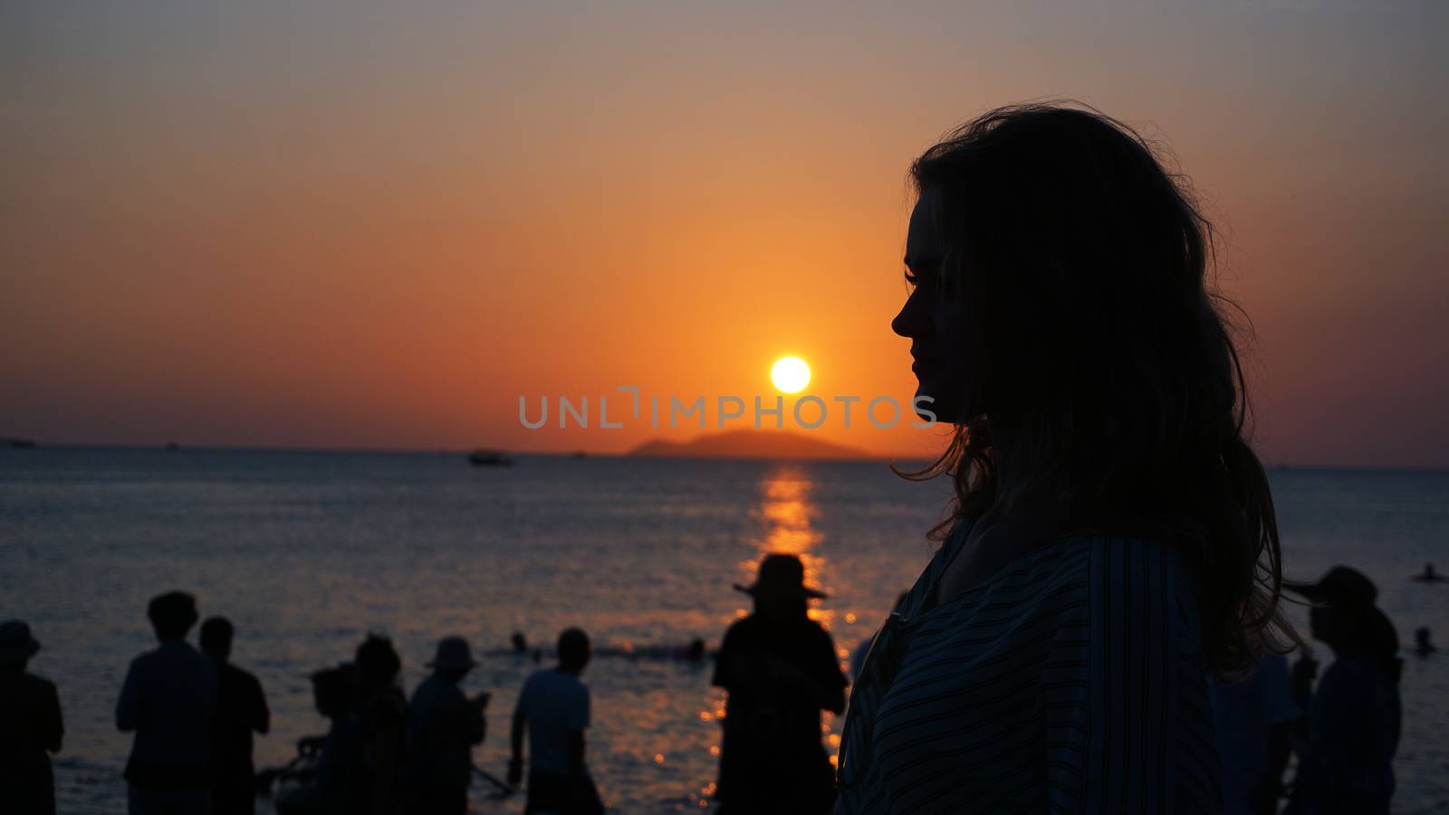 Side view of back light of a woman silhouette warm sunset in front of sun - tourist beach at sunset
