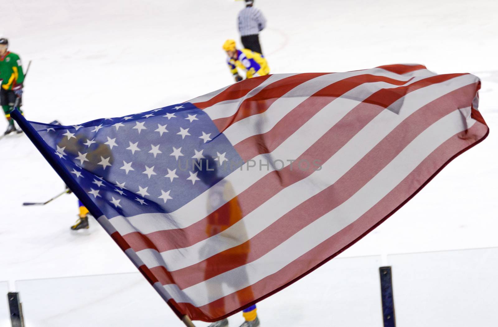 USA flag waving against a defocused hockey game background.