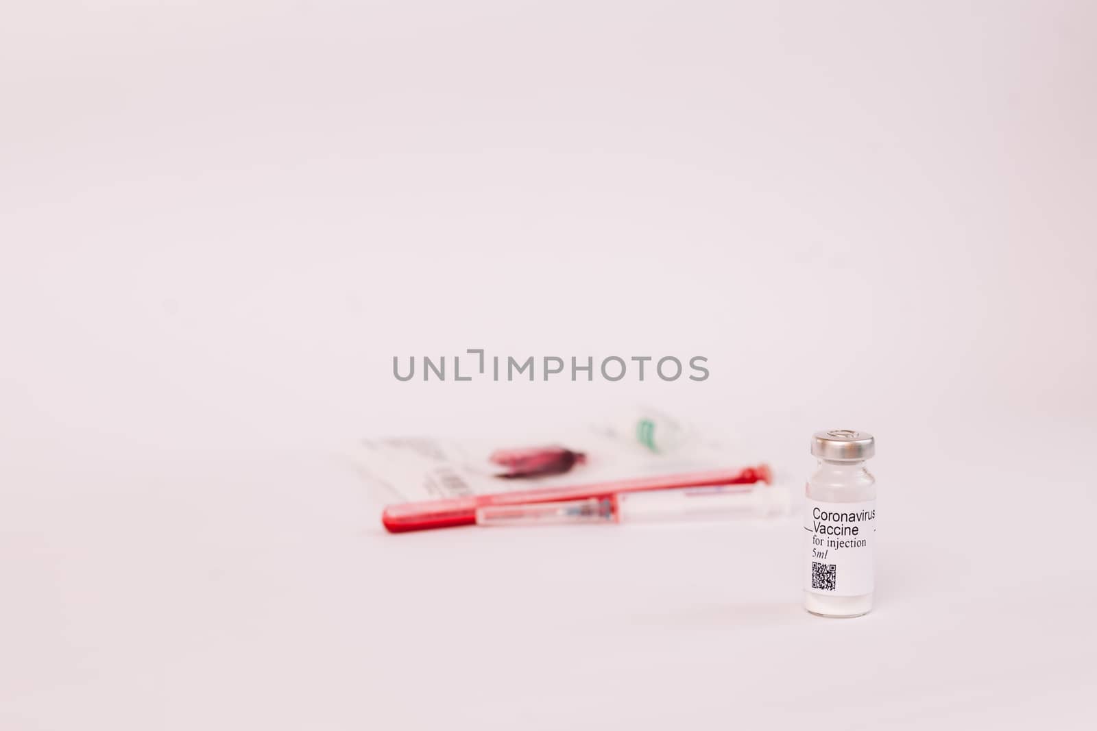 Coronavirus vaccine. Medical preparation in ampoule. Treatment for the disease, covid-19. The vaccine on a white background and on the background of a syringe, rubber gloves and goggles.