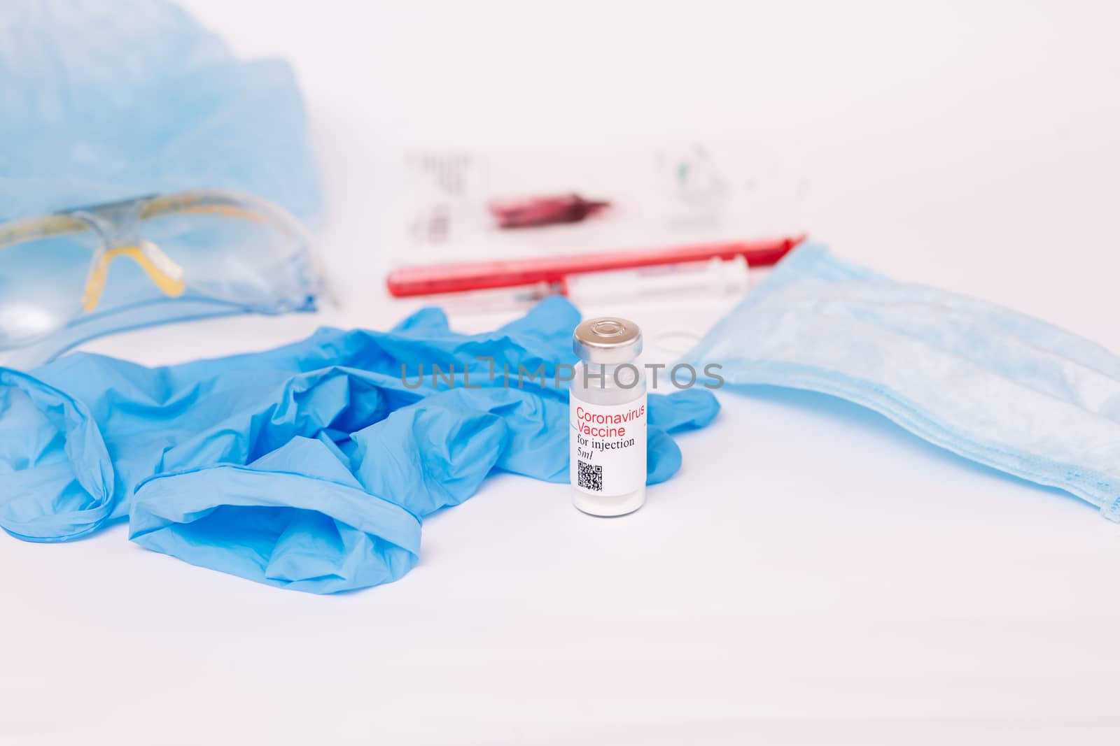 Coronavirus vaccine. Medical preparation in ampoule. Treatment for the disease, covid-19. The vaccine on a white background and on the background of a syringe, rubber gloves and goggles.