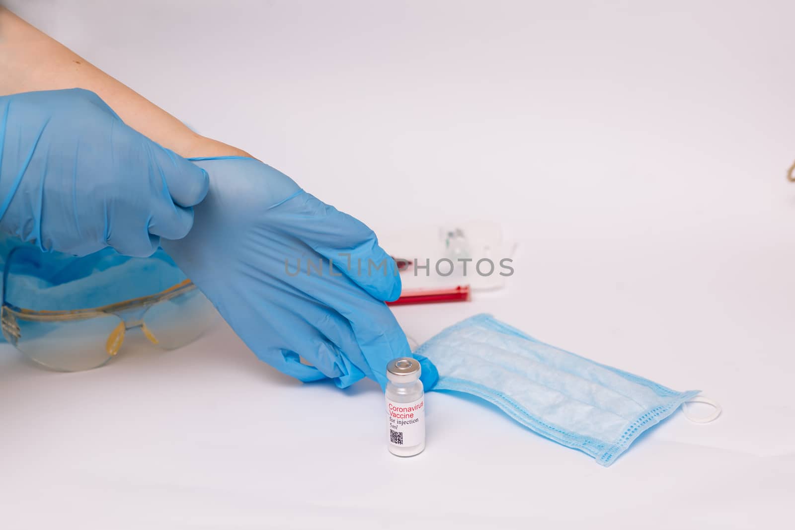 Coronavirus vaccine. Medical preparation in ampoule. Treatment for the disease, covid-19. The vaccine on a white background and on the background of a syringe, rubber gloves and goggles.