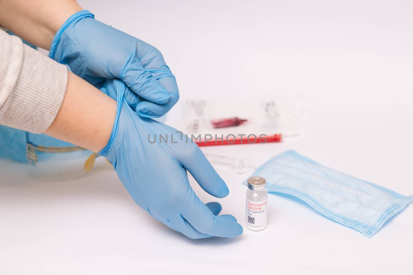 Coronavirus vaccine. Medical preparation in ampoule. Treatment for the disease, covid-19. The vaccine on a white background and on the background of a syringe, rubber gloves and goggles.