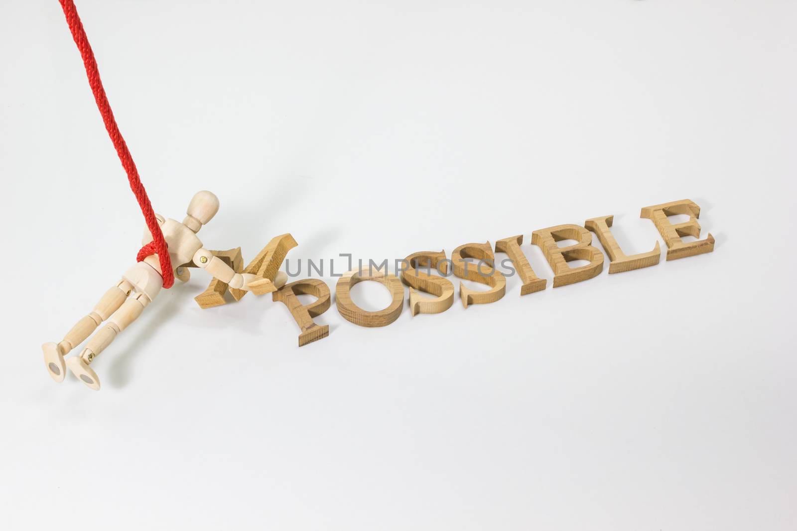 Changing the word impossible to possible with wooden dummy hanging on the red rope