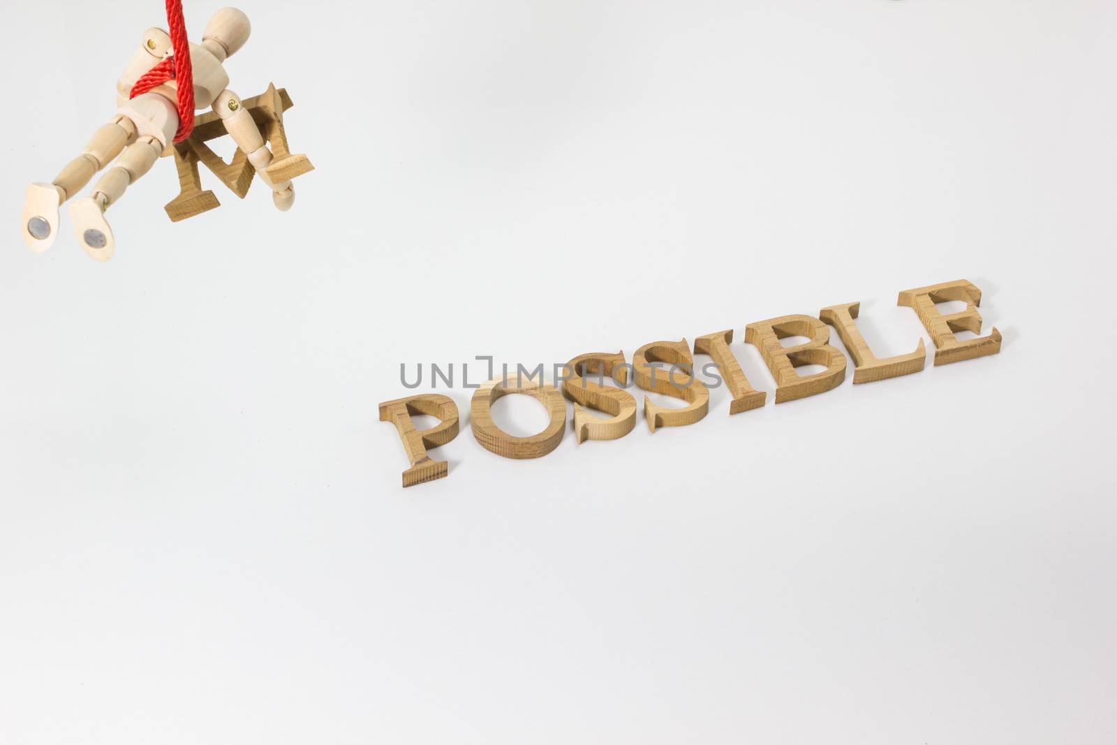 Changing the word impossible to possible with wooden dummy hanging on the red rope