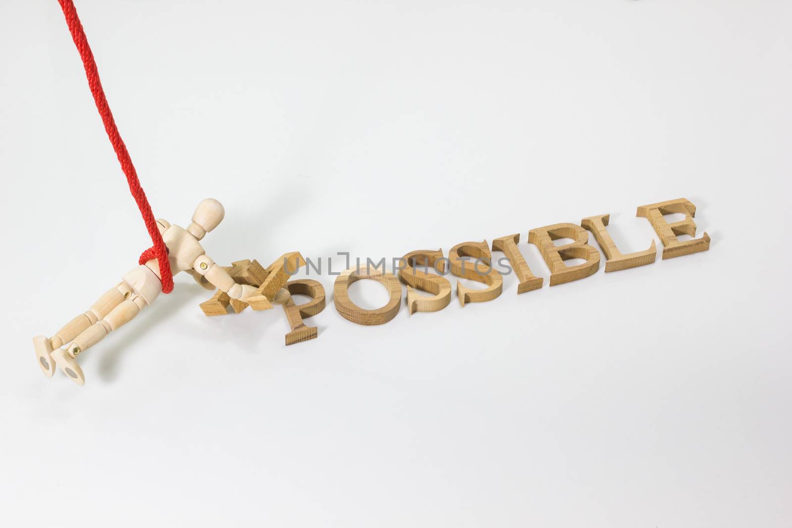 Changing the word impossible to possible with wooden dummy hanging on the red rope