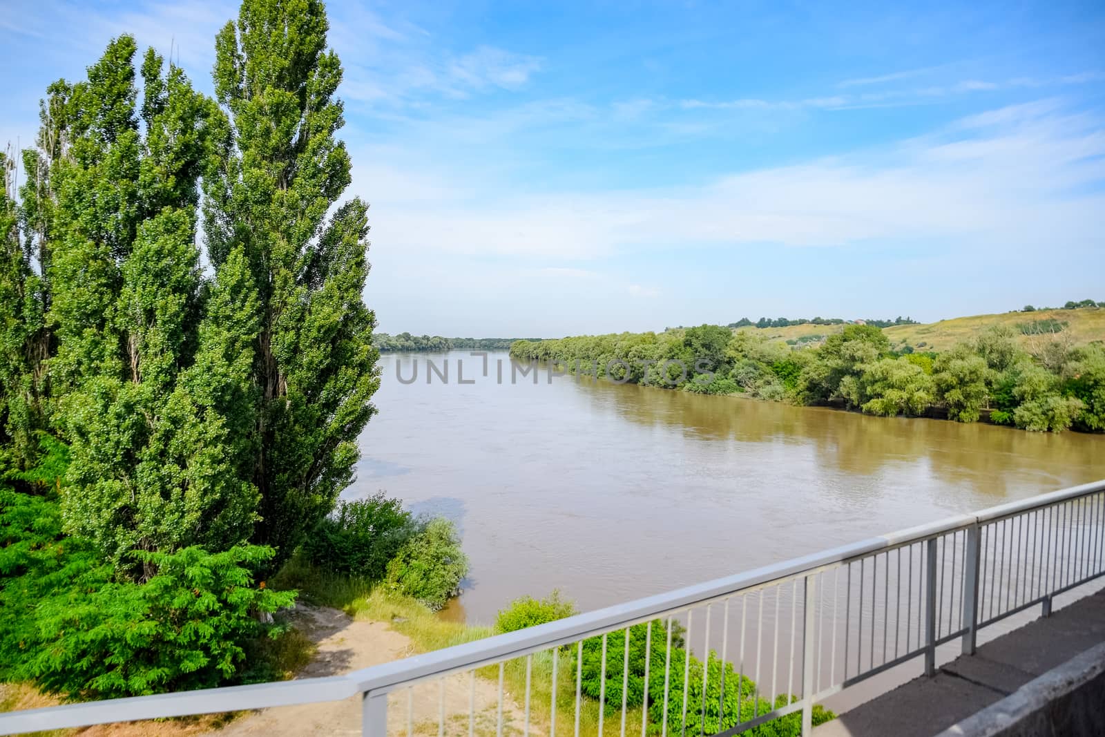 Passing over the bridge over the river. The landscape of the river, the surface and the trees of the river's waterplain.