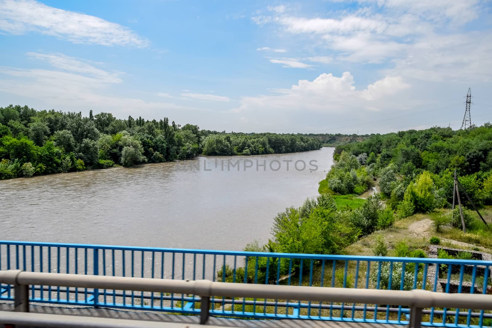 Passing over the bridge over the river. The landscape of the river, the surface and the trees of the river's waterplain.