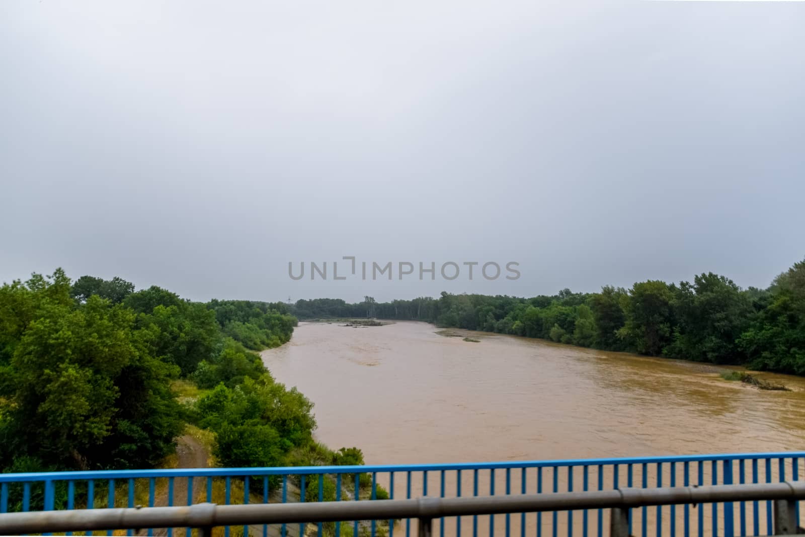 Passing over the bridge over the river. The landscape of the river, the surface and the trees of the river's waterplain.