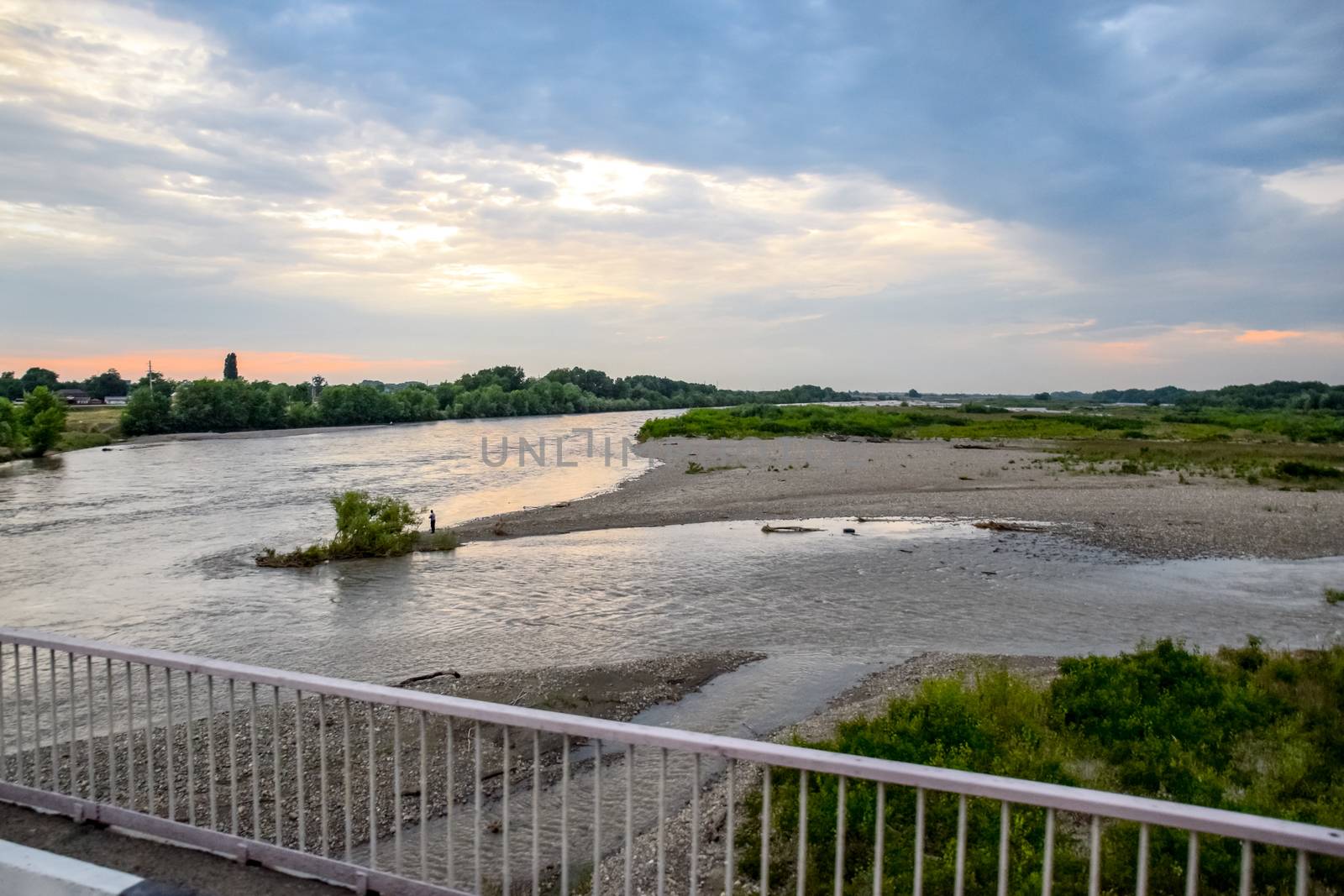 Passing over the bridge over the river. The landscape of the river, the surface and the trees of the river's waterplain.