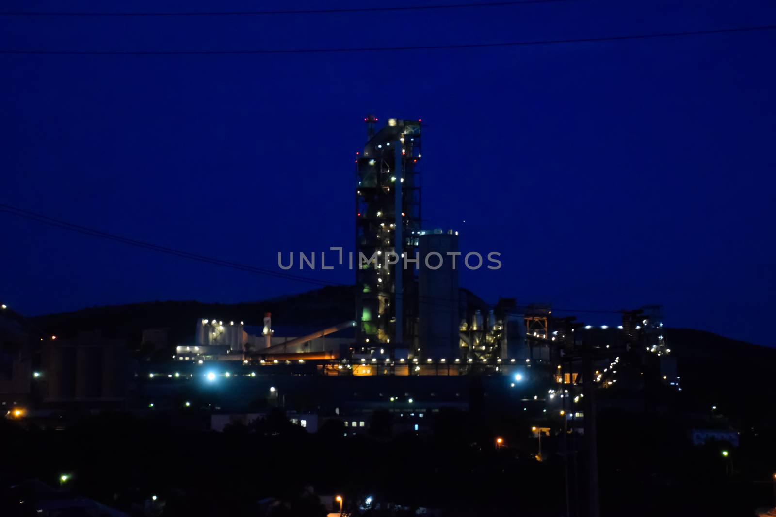 The building of a cement plant at night, the lights of a lamp lighting a factory. Industrial facility.