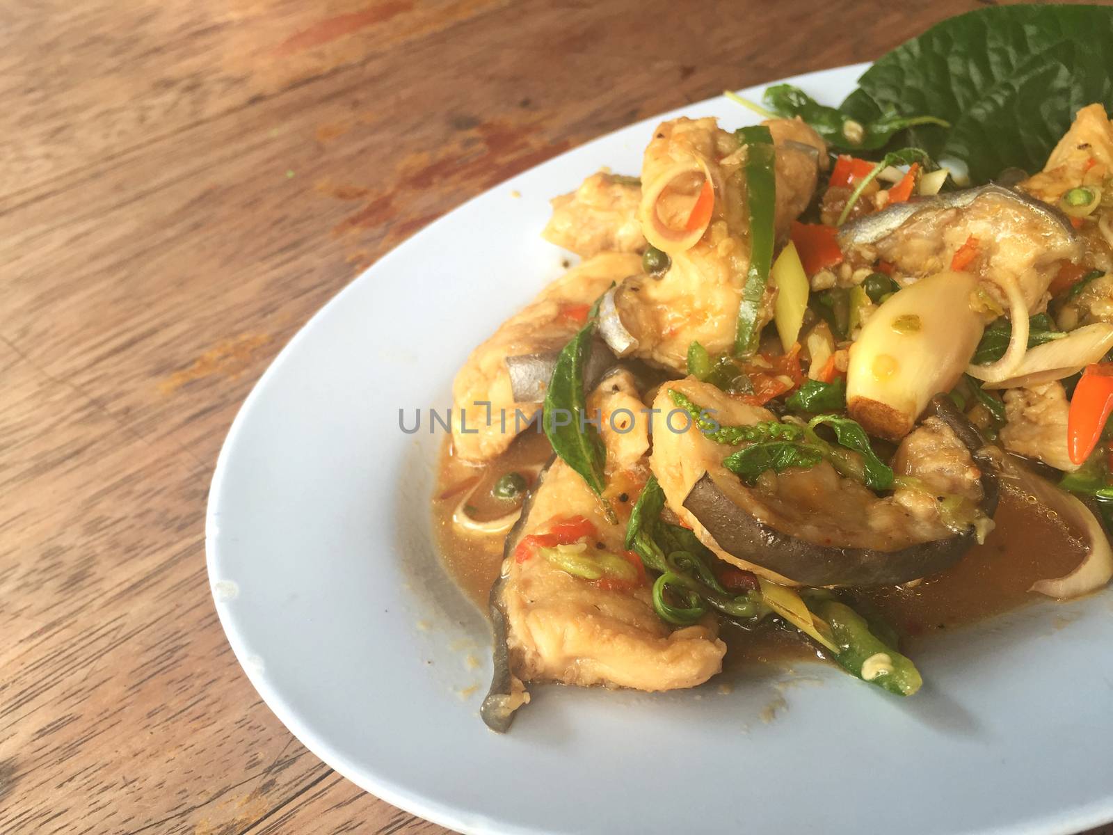 horizontal photo of fried spicy Mekong giant catfish with herb on wooden background, copyspace