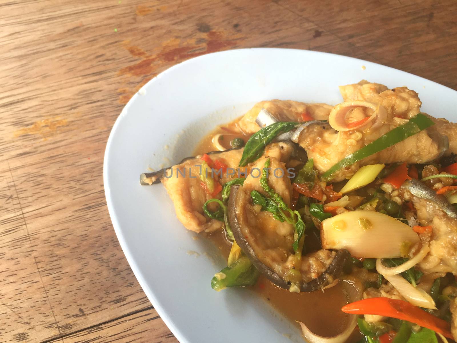 horizontal photo of fried spicy Mekong giant catfish with herb on wooden background, copyspace