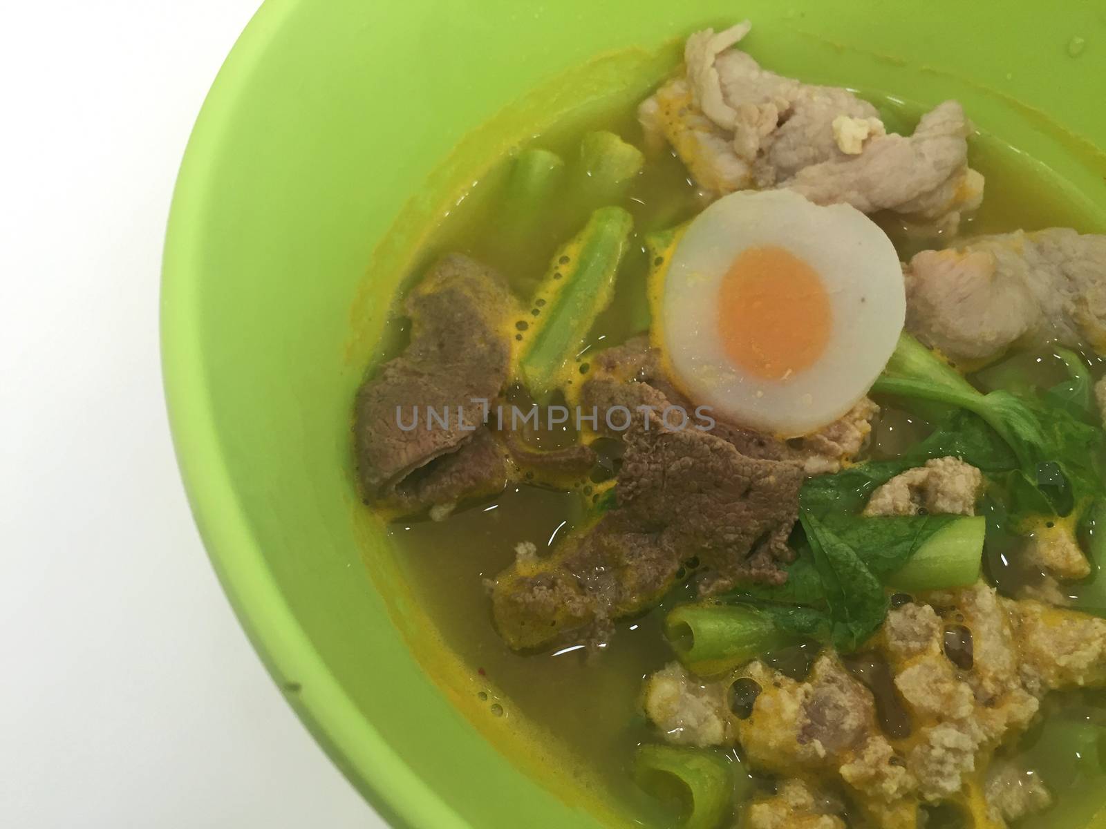 horizontal photo of noodles on green bowl with pork and vegetables