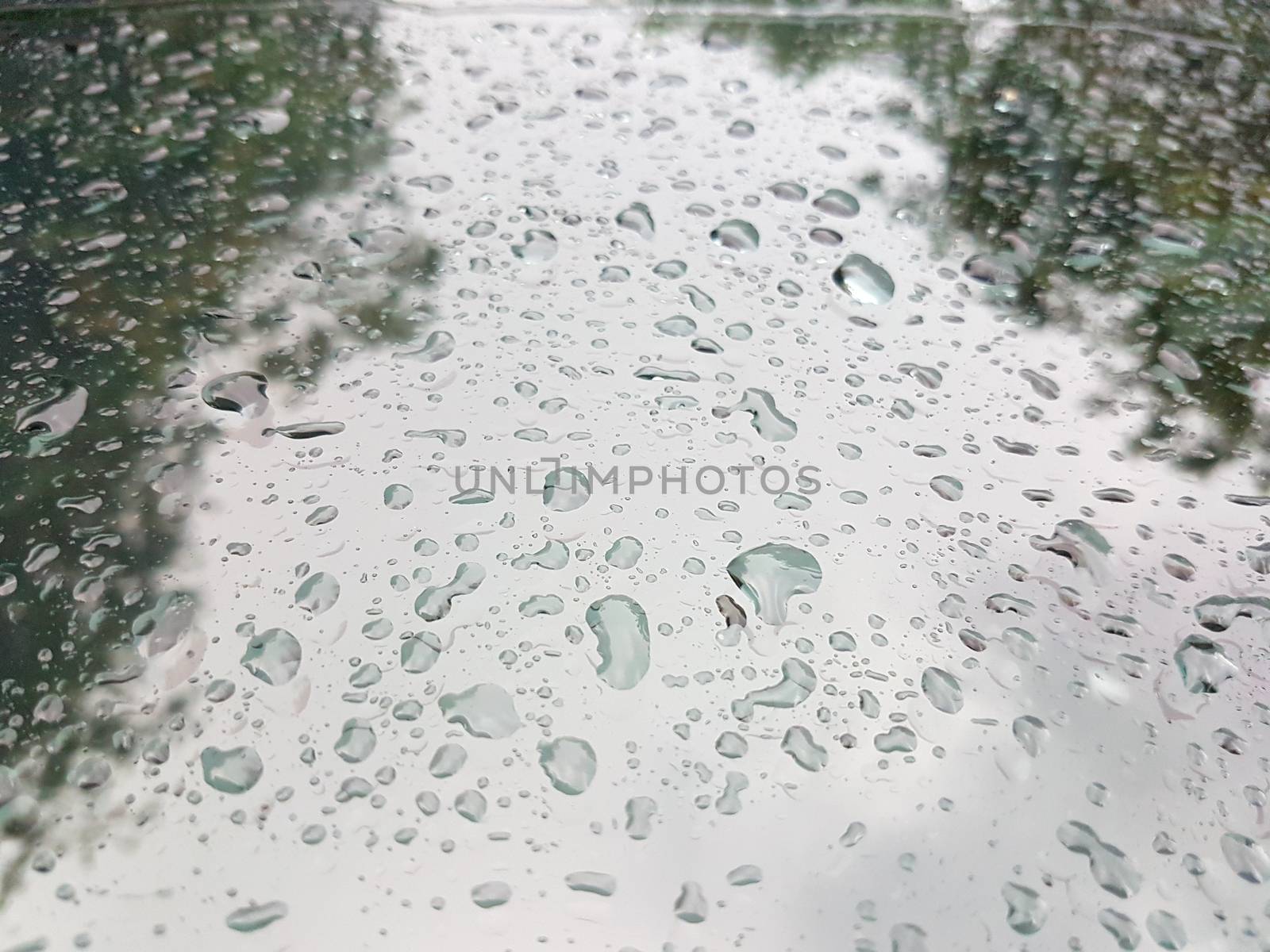 Rain drops in front of the car window with reflection