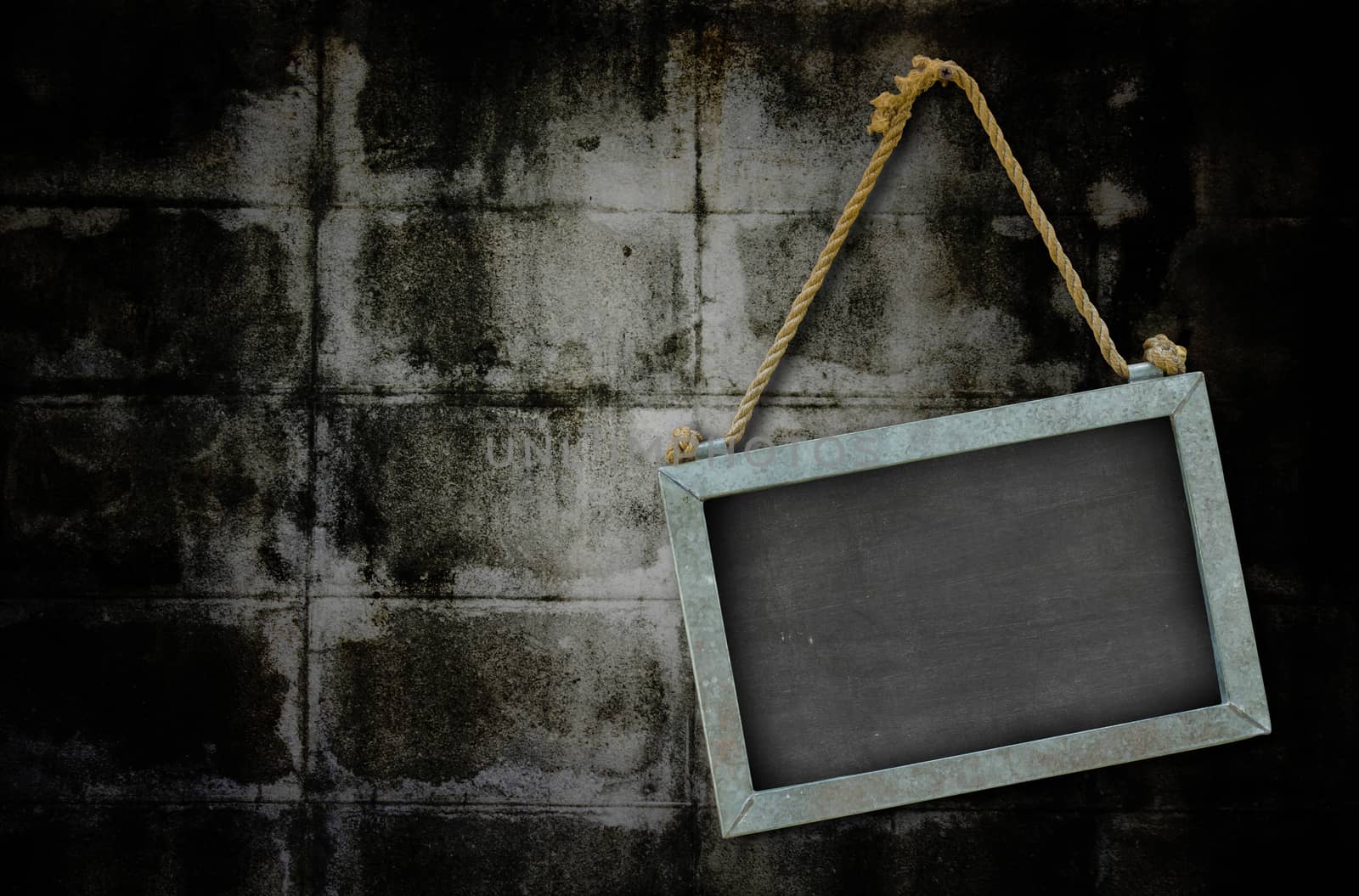 iron blackboard hanging on old grunge wall texture with vignette.