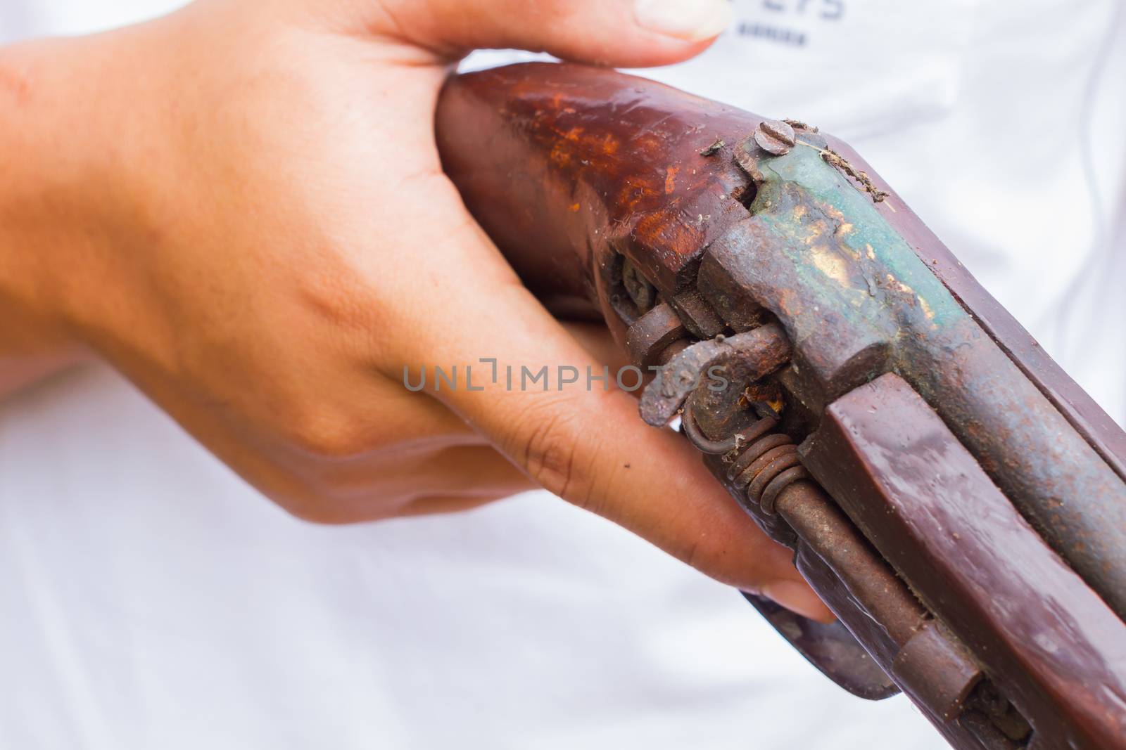 horizontal photo of closeup hand holding old gun, selective focus on the gun.