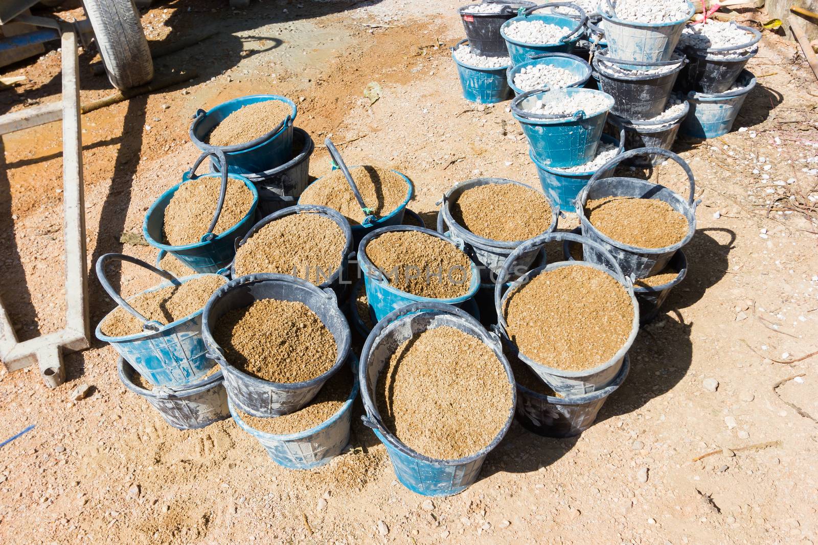 sand in many buckets prepared for mixing cement or concrete in construction site, horizontal photo.