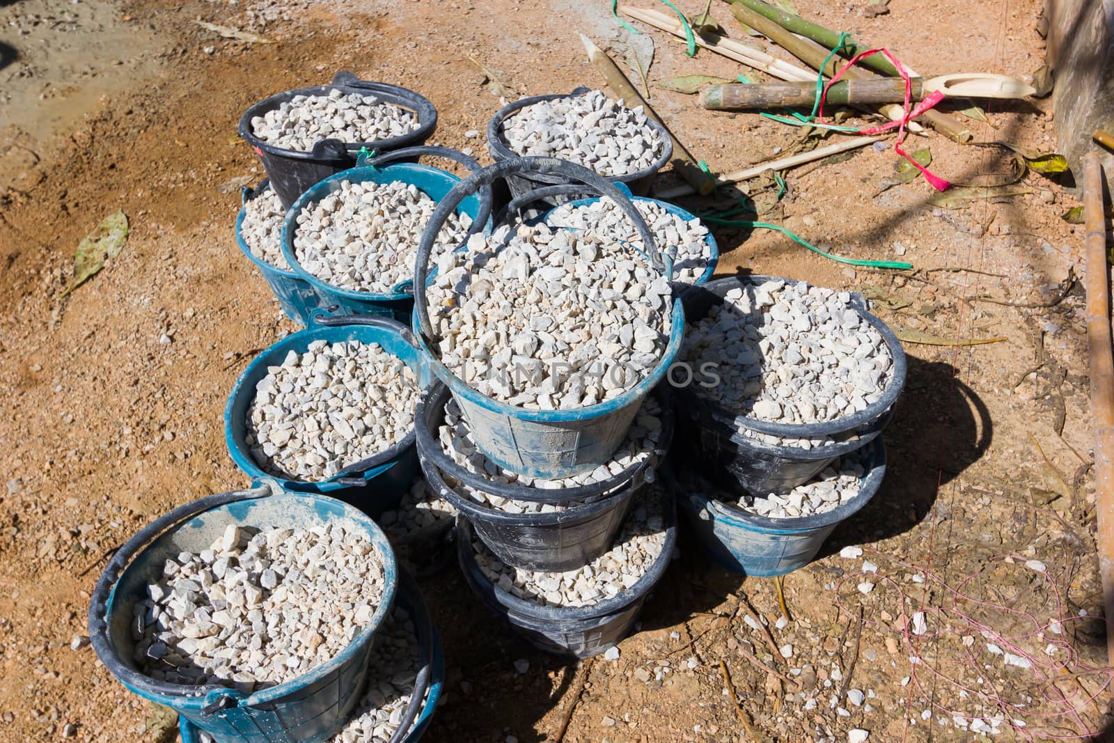 pebbles in many buckets prepared for mixing cement or concrete in construction site, horizontal photo.