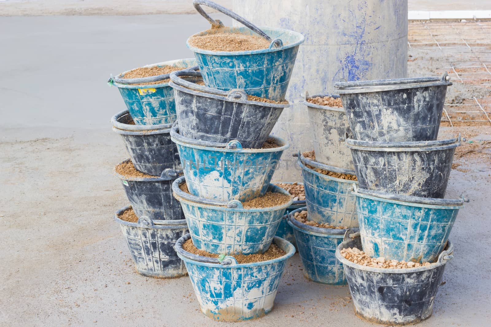 sand in many buckets prepared for mixing cement or concrete in construction site, horizontal photo.