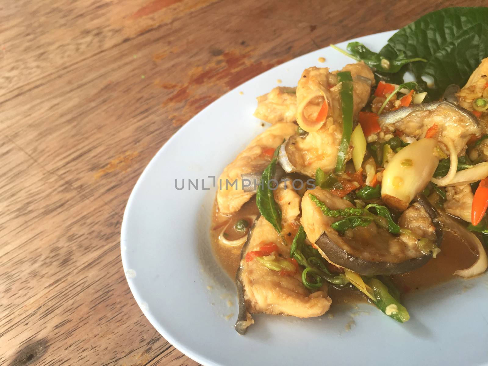 horizontal photo of fried spicy Mekong giant catfish with herb on wooden background, copyspace