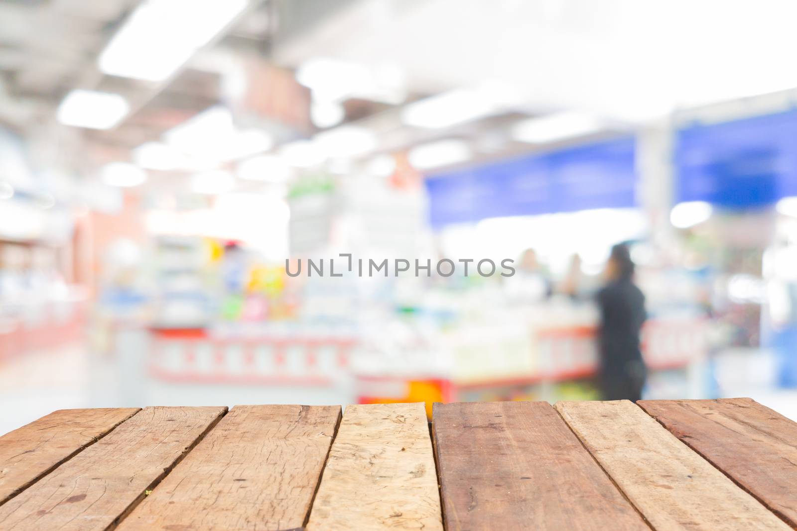 Wooden board empty table in front of blurred convenience store cashier background with bokeh
