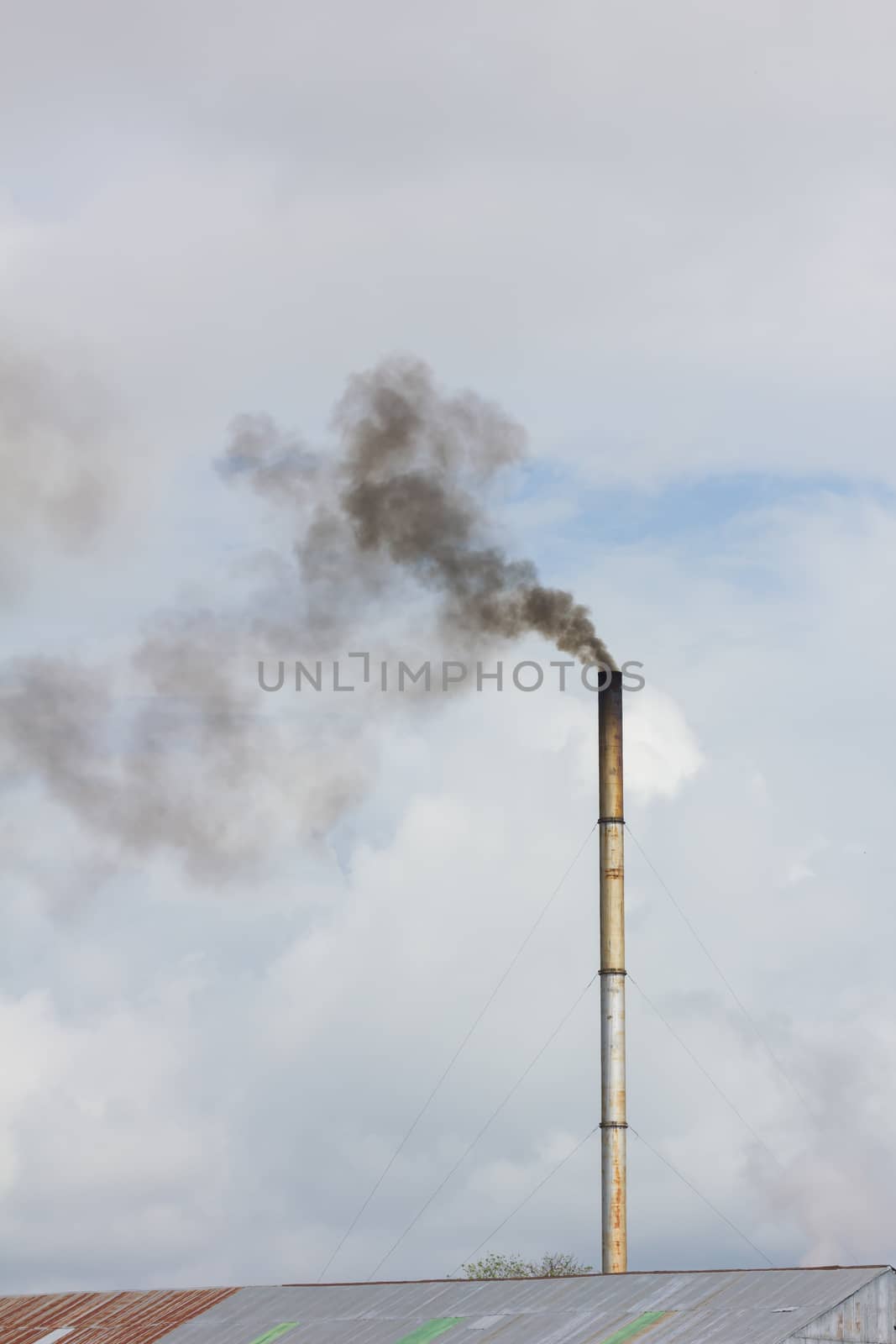 smoke from chimney of rice mill in thailand, vertical photo.