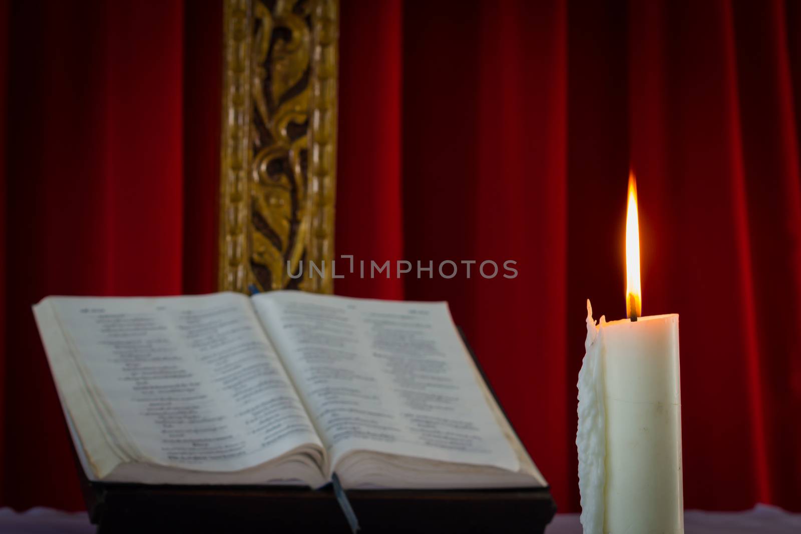 Open book and burning candle on dark