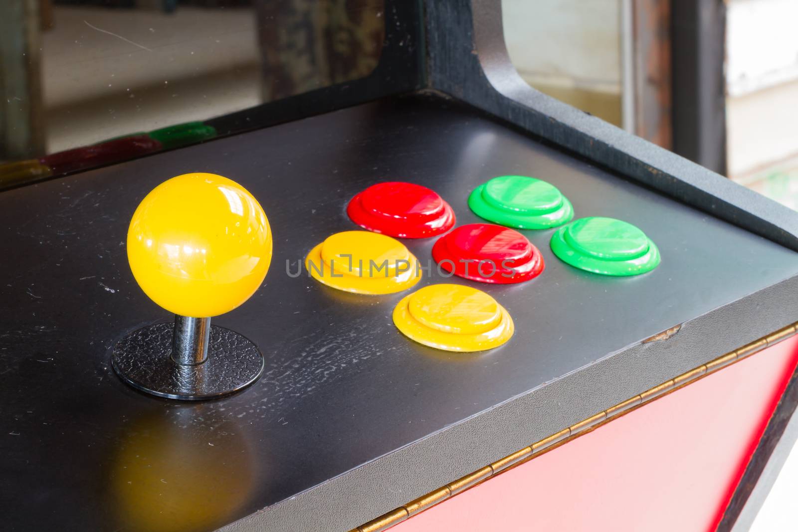 yellow joystick of an old arcade video game with six colorful button