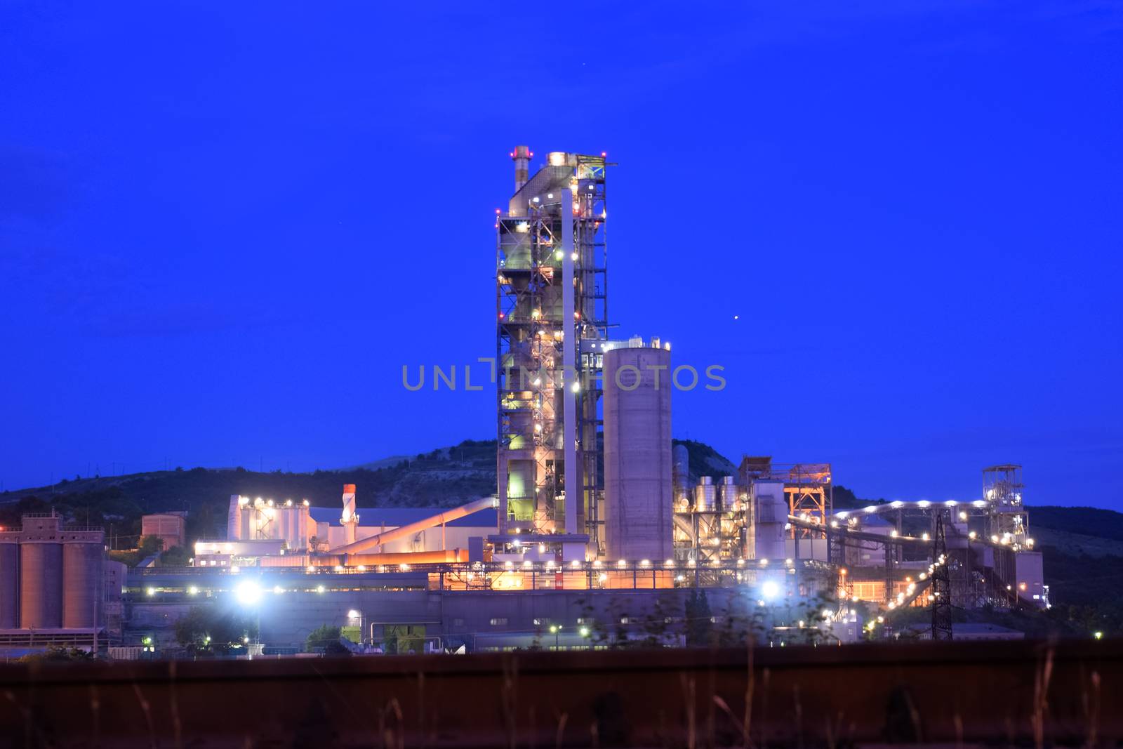 The building of a cement plant at night, the lights of a lamp lighting a factory. Industrial facility.