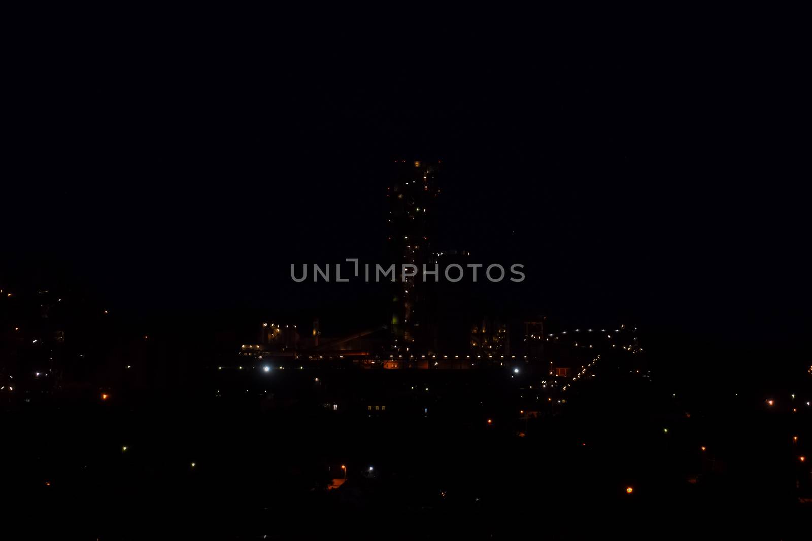The building of a cement plant at night, the lights of a lamp lighting a factory. Industrial facility.