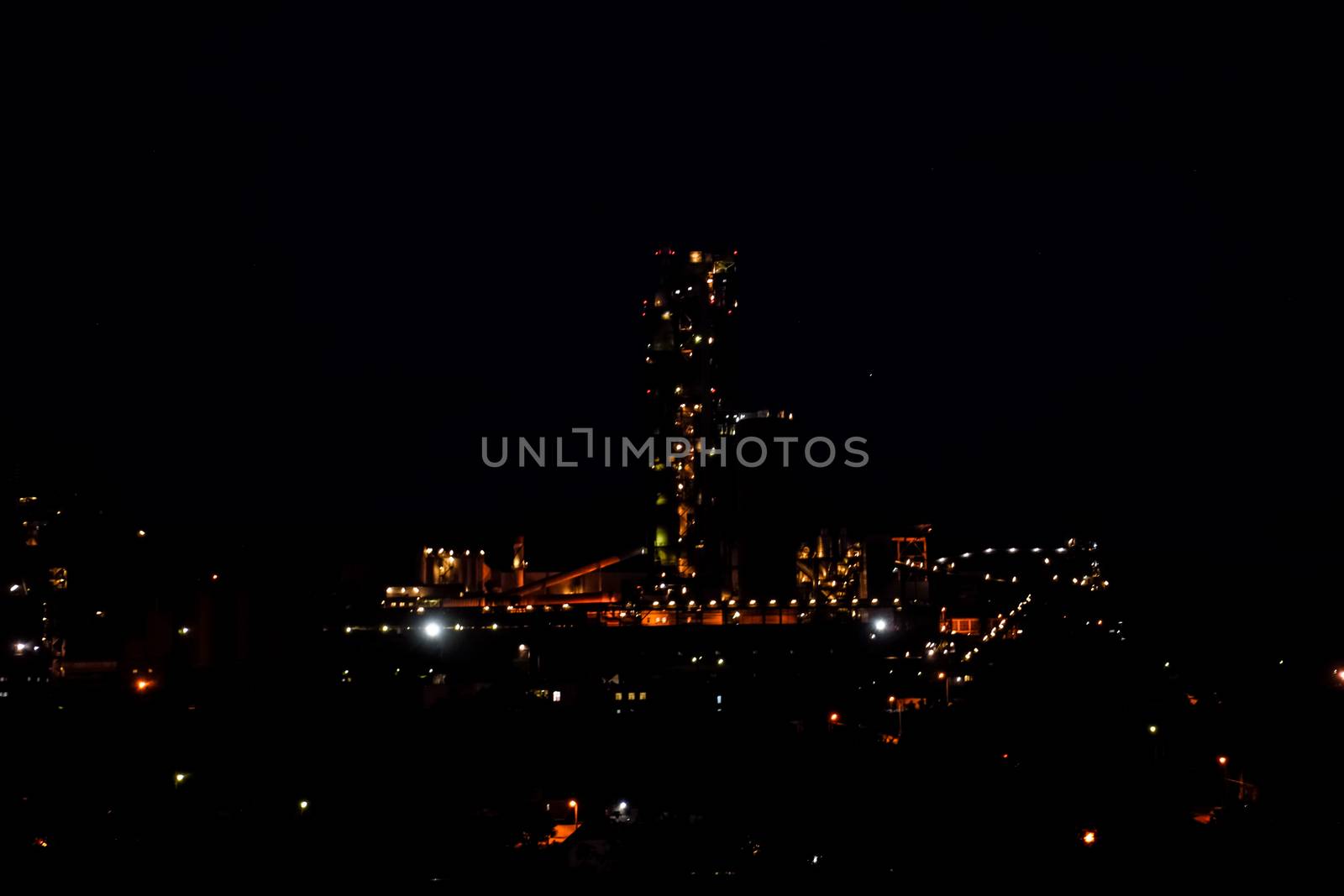 The building of a cement plant at night, the lights of a lamp lighting a factory. Industrial facility.