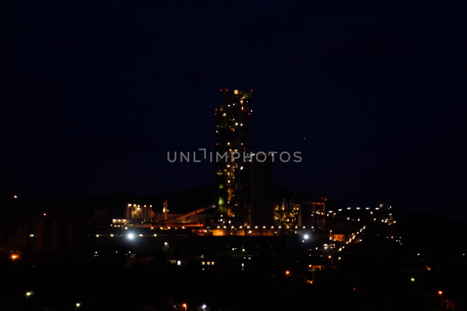 The building of a cement plant at night, the lights of a lamp lighting a factory. Industrial facility.