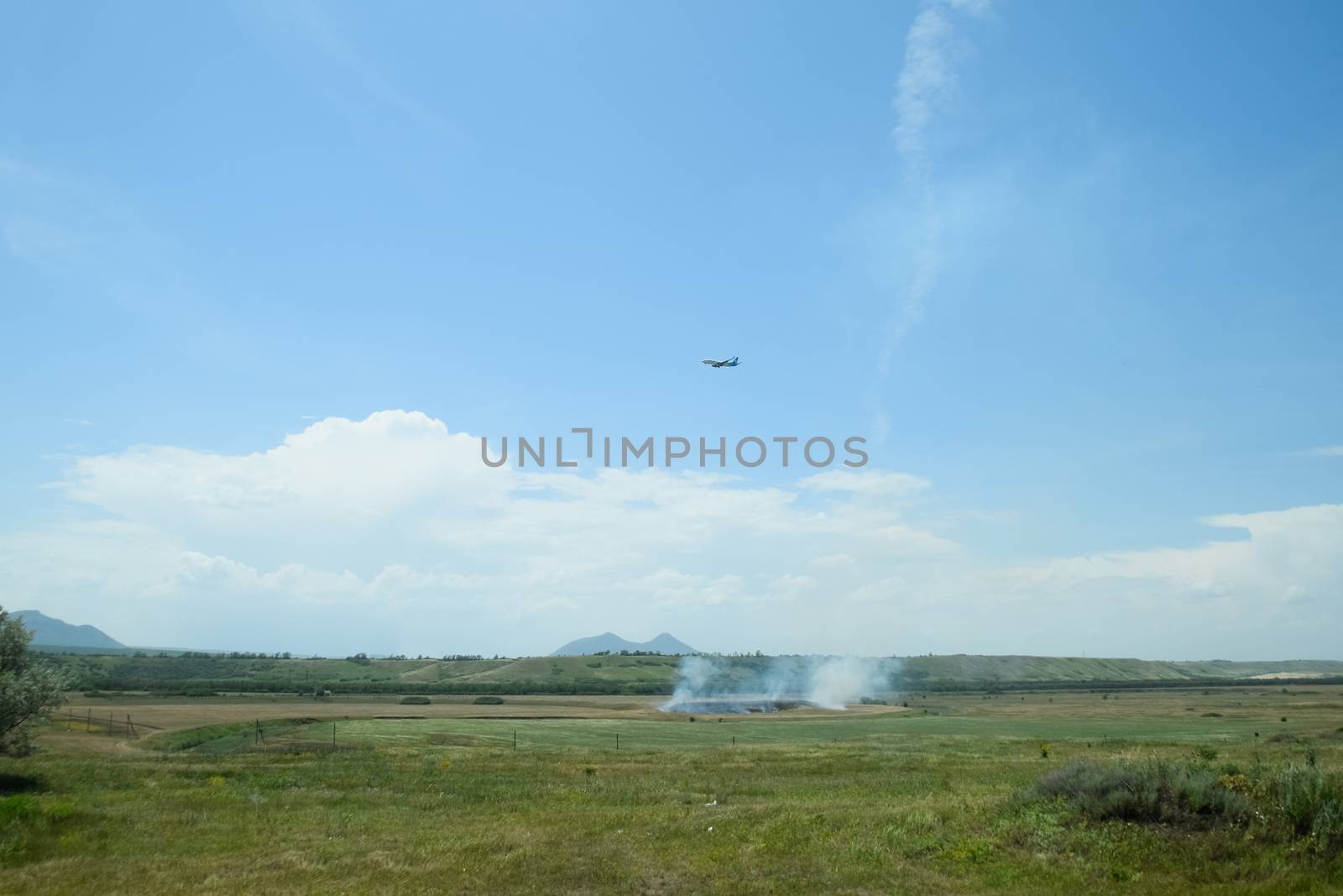 The plane sets up, flying over the field where the dry grass burns