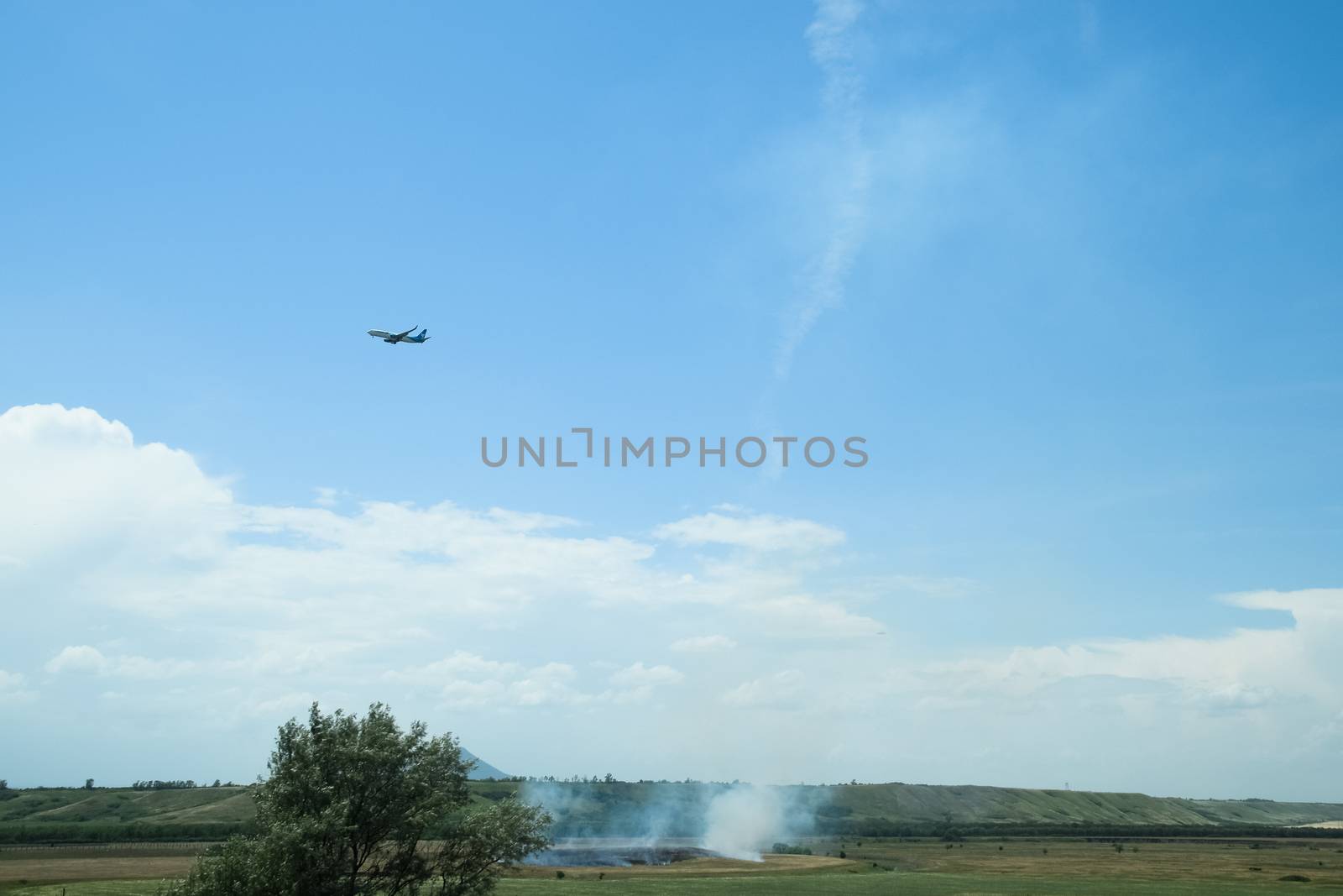 The plane sets up, flying over the field where the dry grass burns